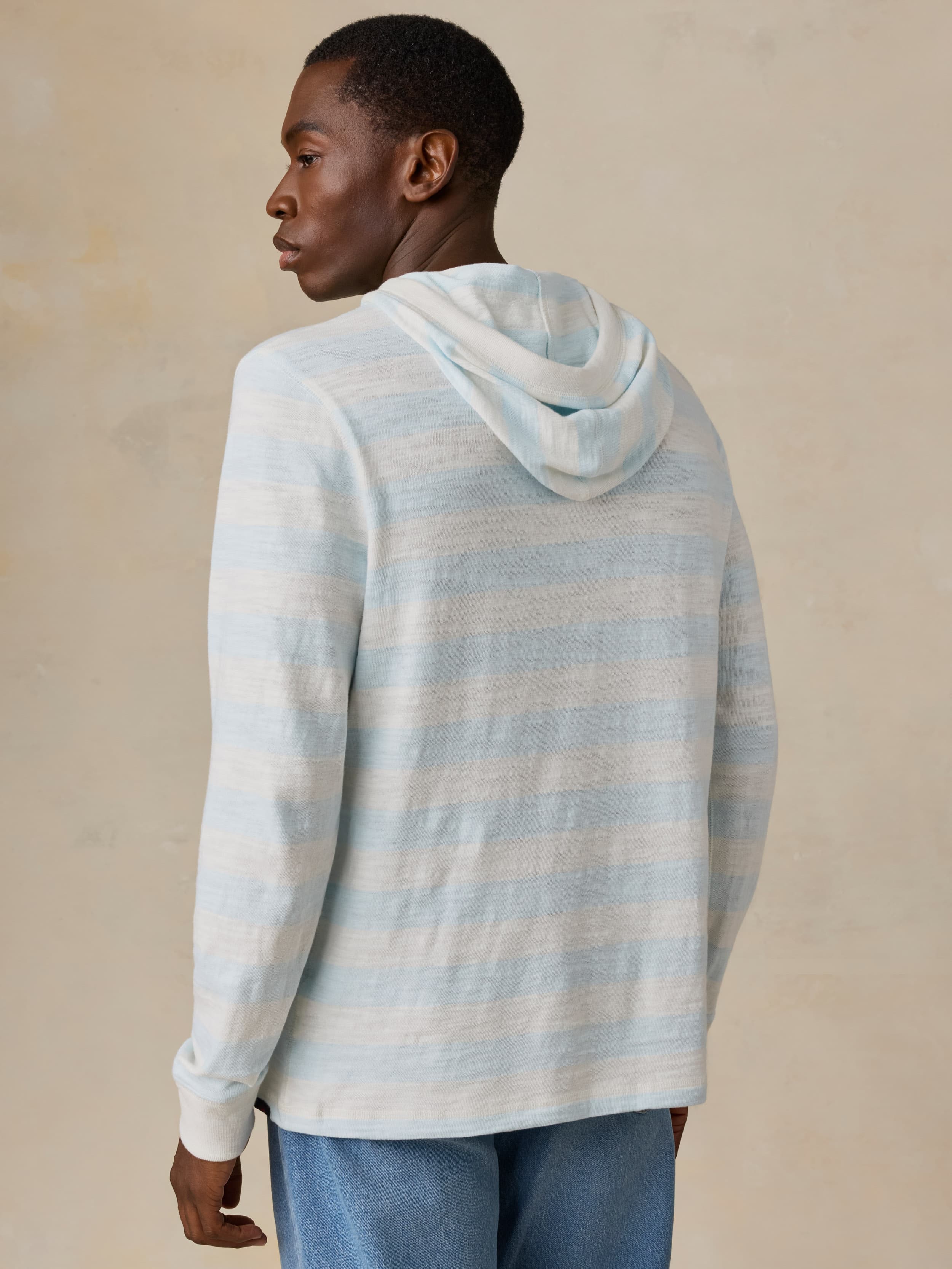 Man wearing a light blue and white striped hoodie on a beige background