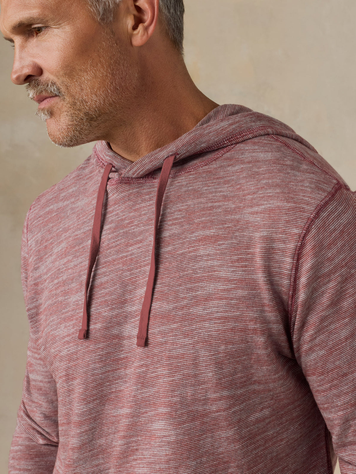 Man wearing a red heathered hoodie against a beige background, image 5 of 5