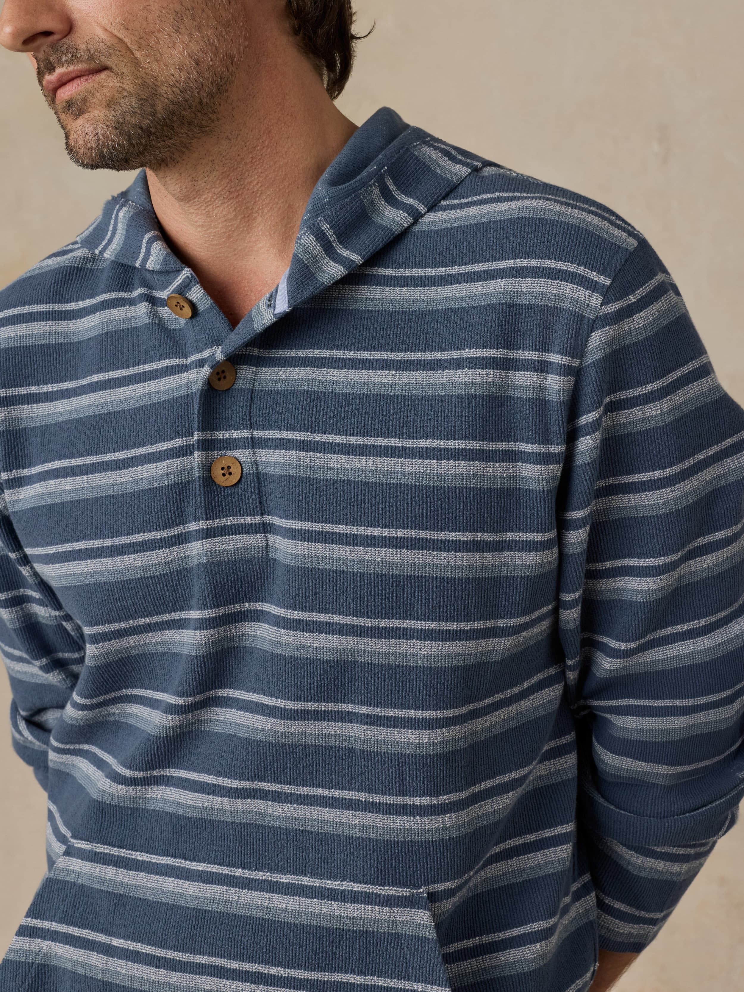 Man wearing a blue striped hoodie against a beige background