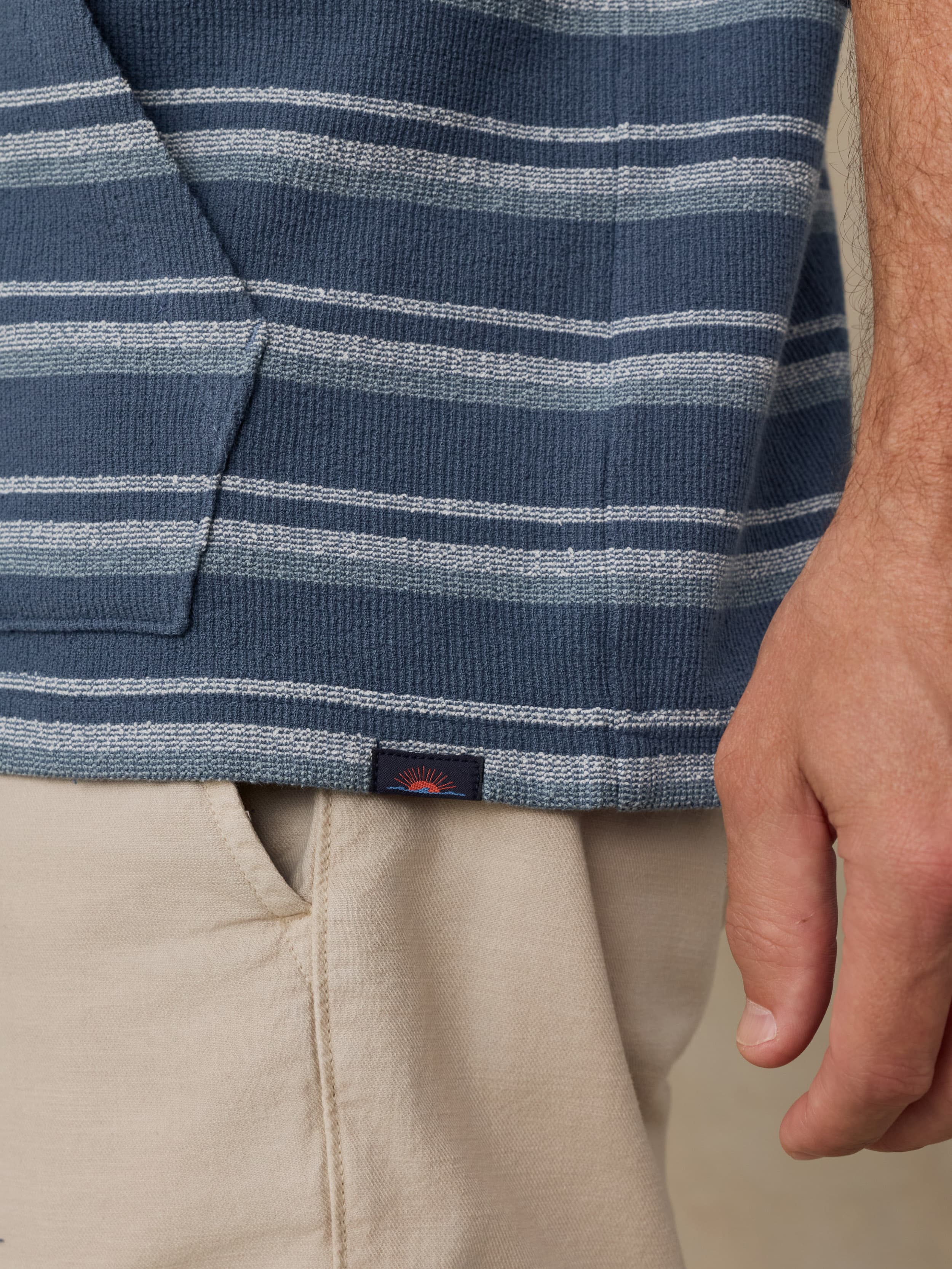 Close-up of a man wearing a blue and gray striped hoodie with a visible Faherty brand logo.