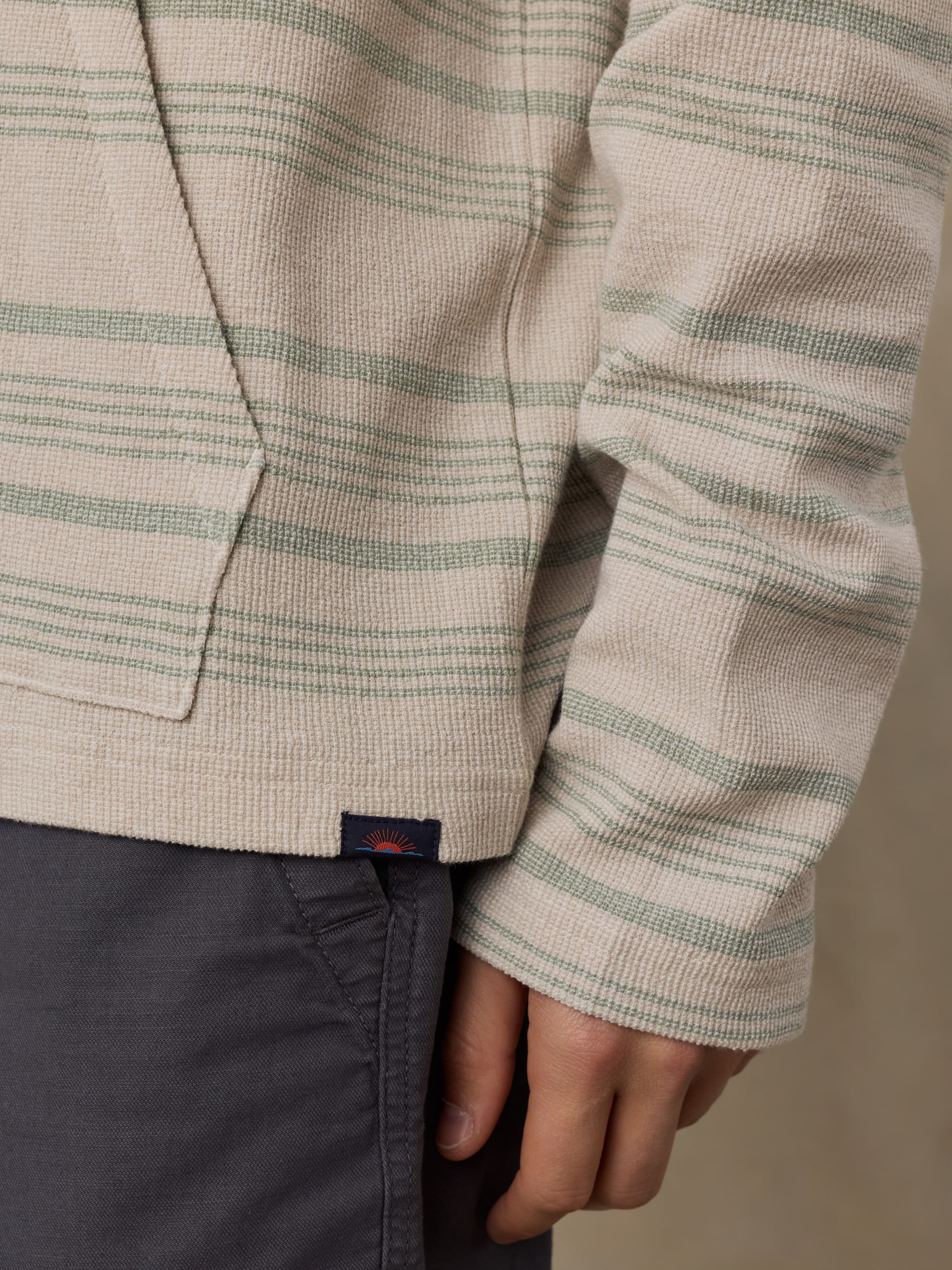 Close-up of a person wearing a beige and green striped sweatshirt