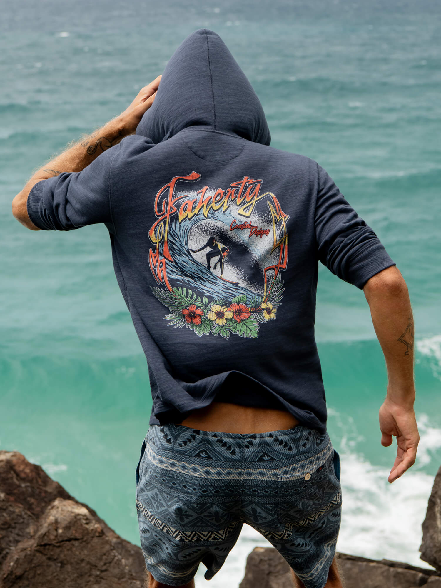Man wearing a hoodie with a graphic design by the ocean