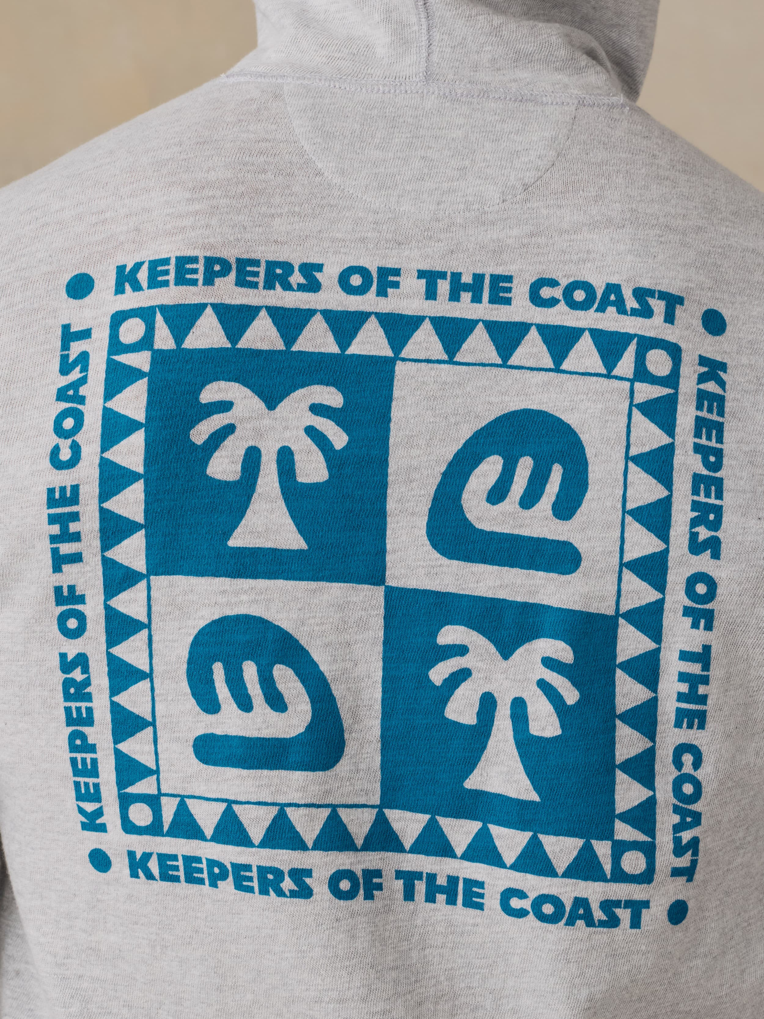 Man wearing a gray hoodie with a Faherty x Surfrider Foundation logo on a beige background
