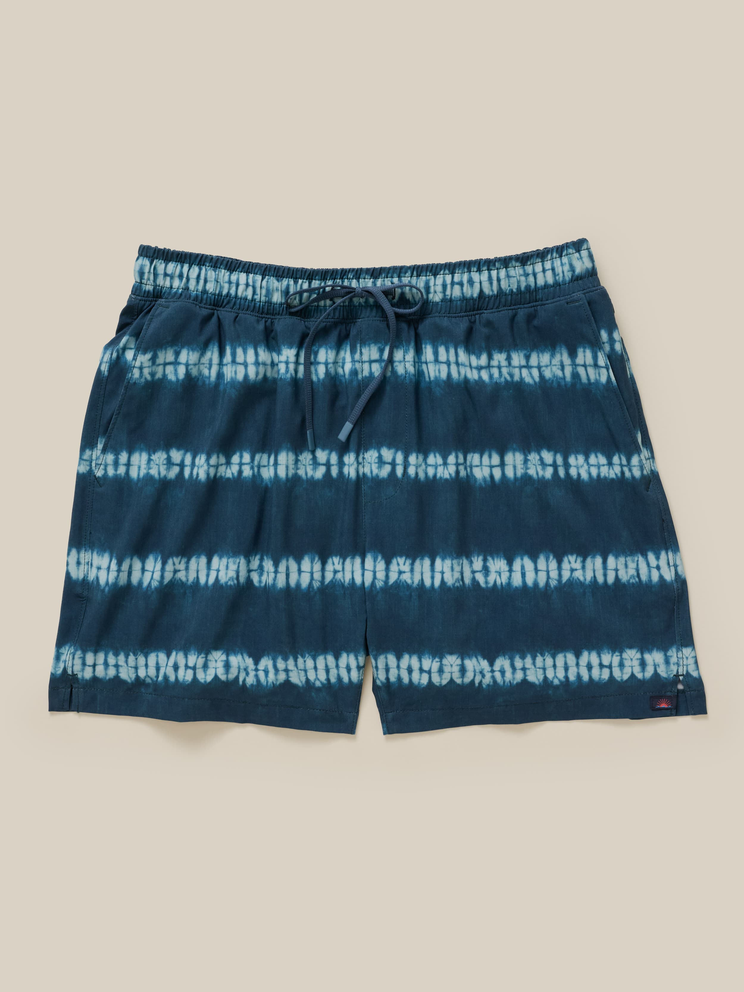 Blue tie-dye shorts on a beige background