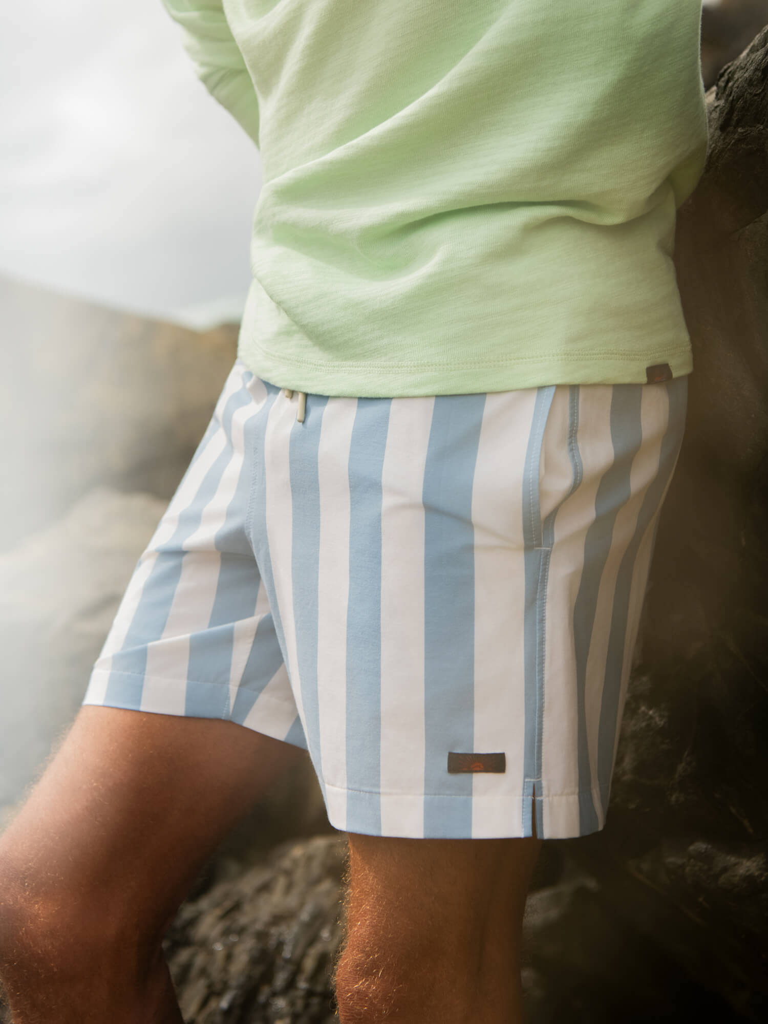 Man wearing a green hoodie with blue and white swim trunks