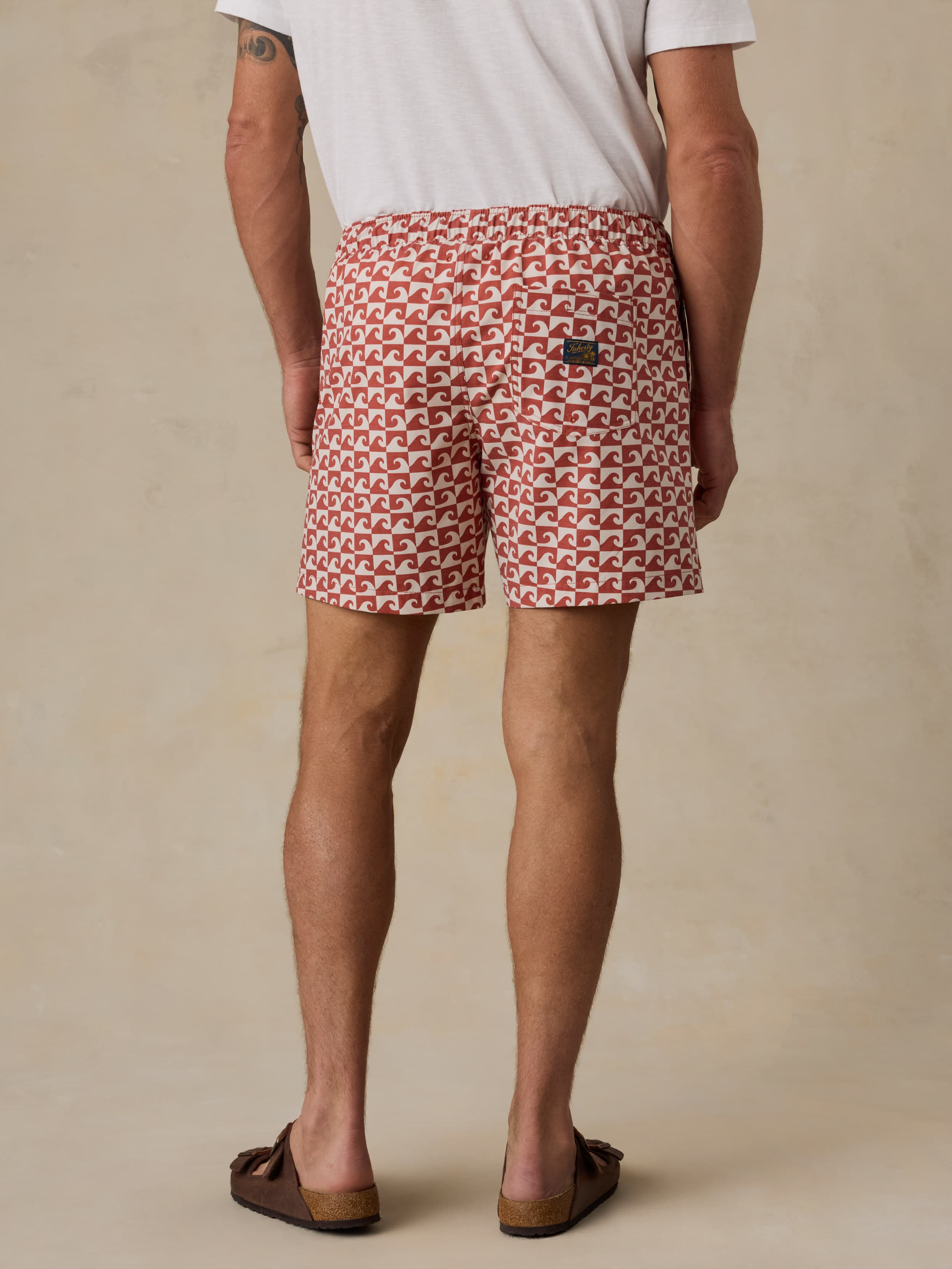 Man wearing red patterned swim shorts on a beige background