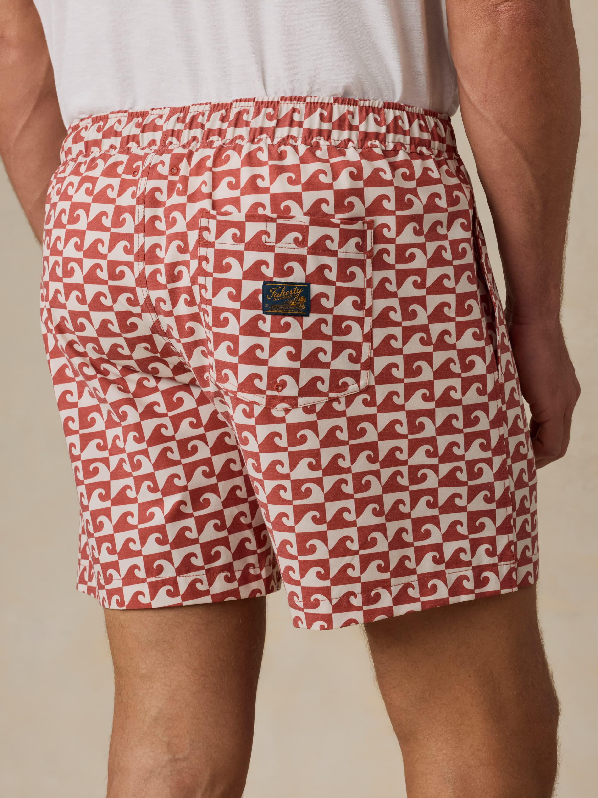 Man wearing a red and white patterned shorts worn by a person on a beige background