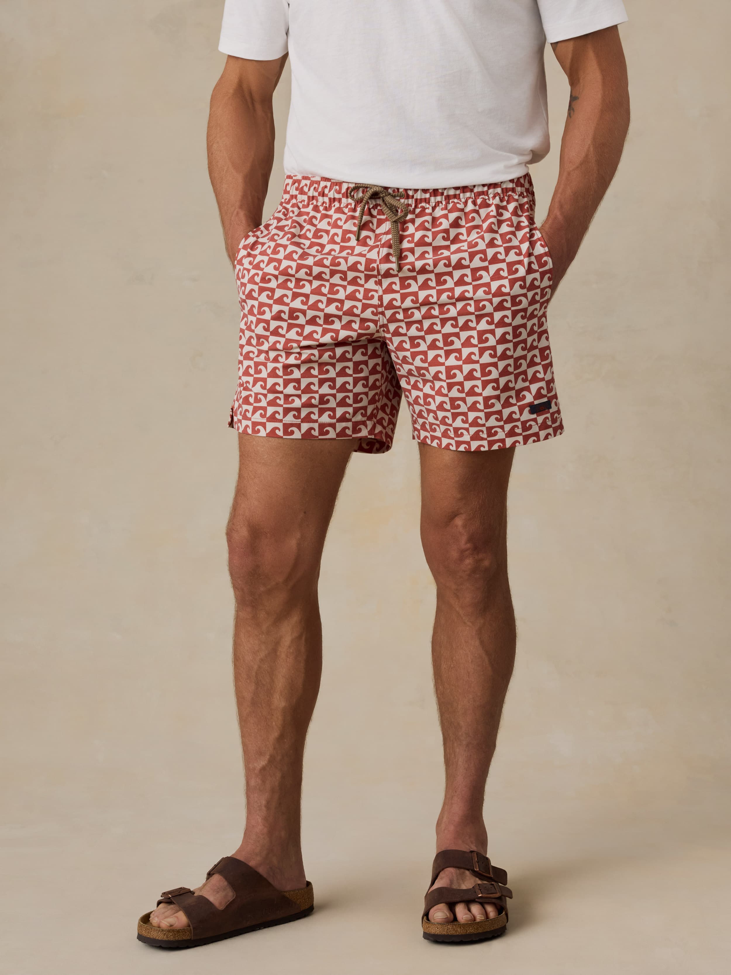 Man wearing red patterned swim shorts on a beige background