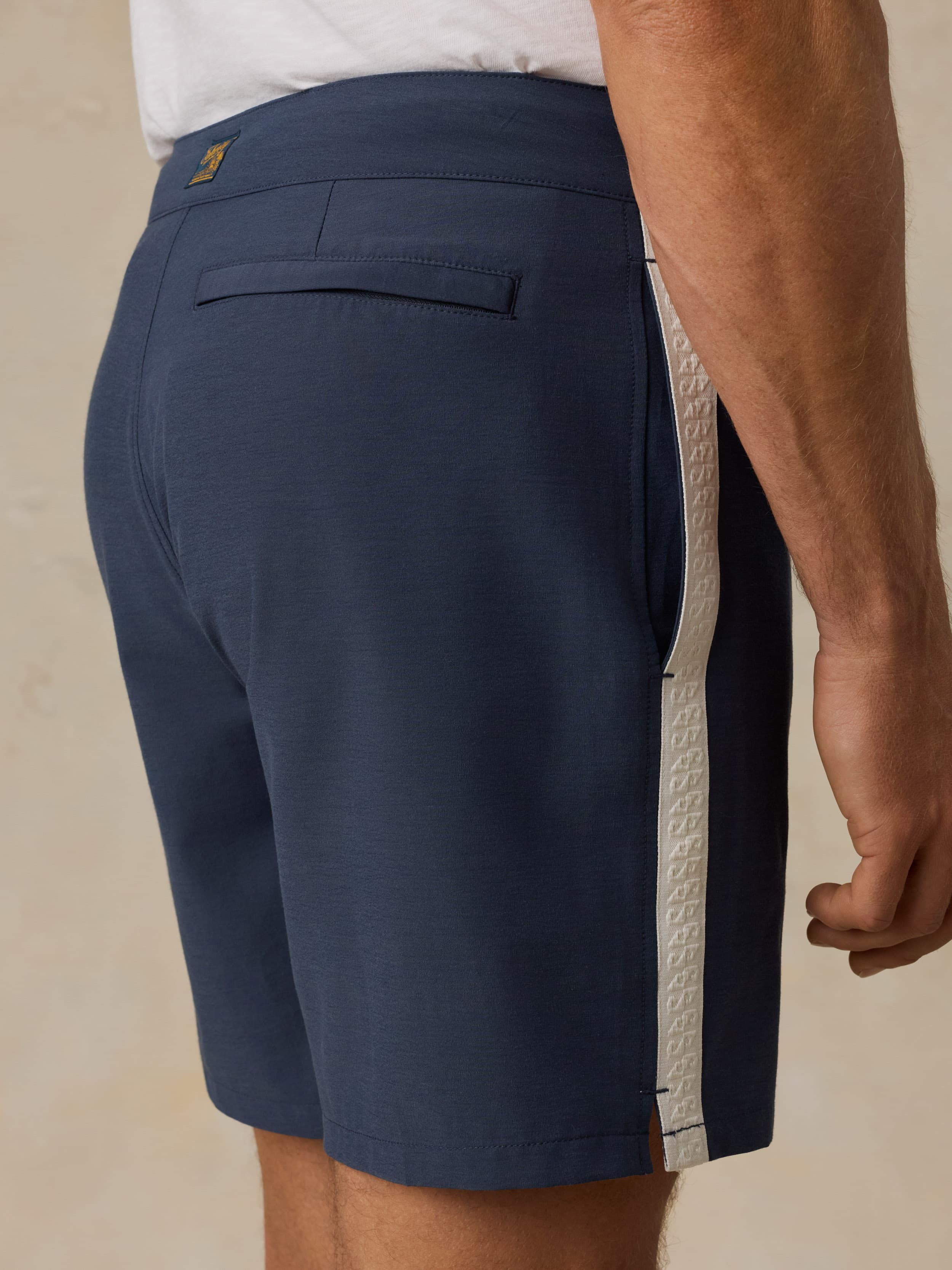 Navy swim shorts with a white stripe on a beige background