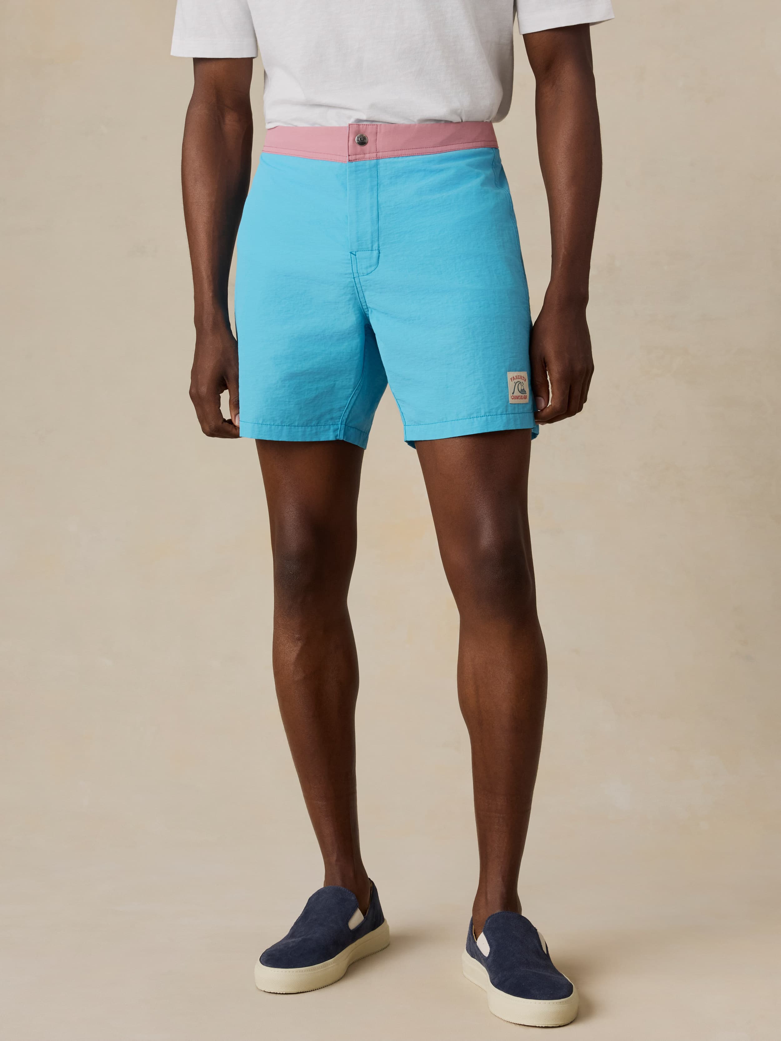 Man wearing turquoise swim  shorts with a plain background