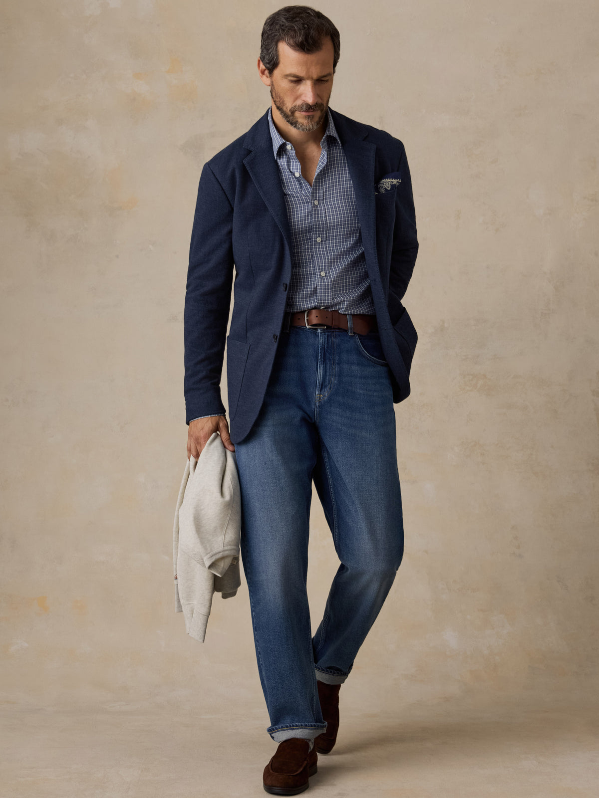 Man wearing a navy blazer over a blue button up shirt and blue jeans, image 5 of 5