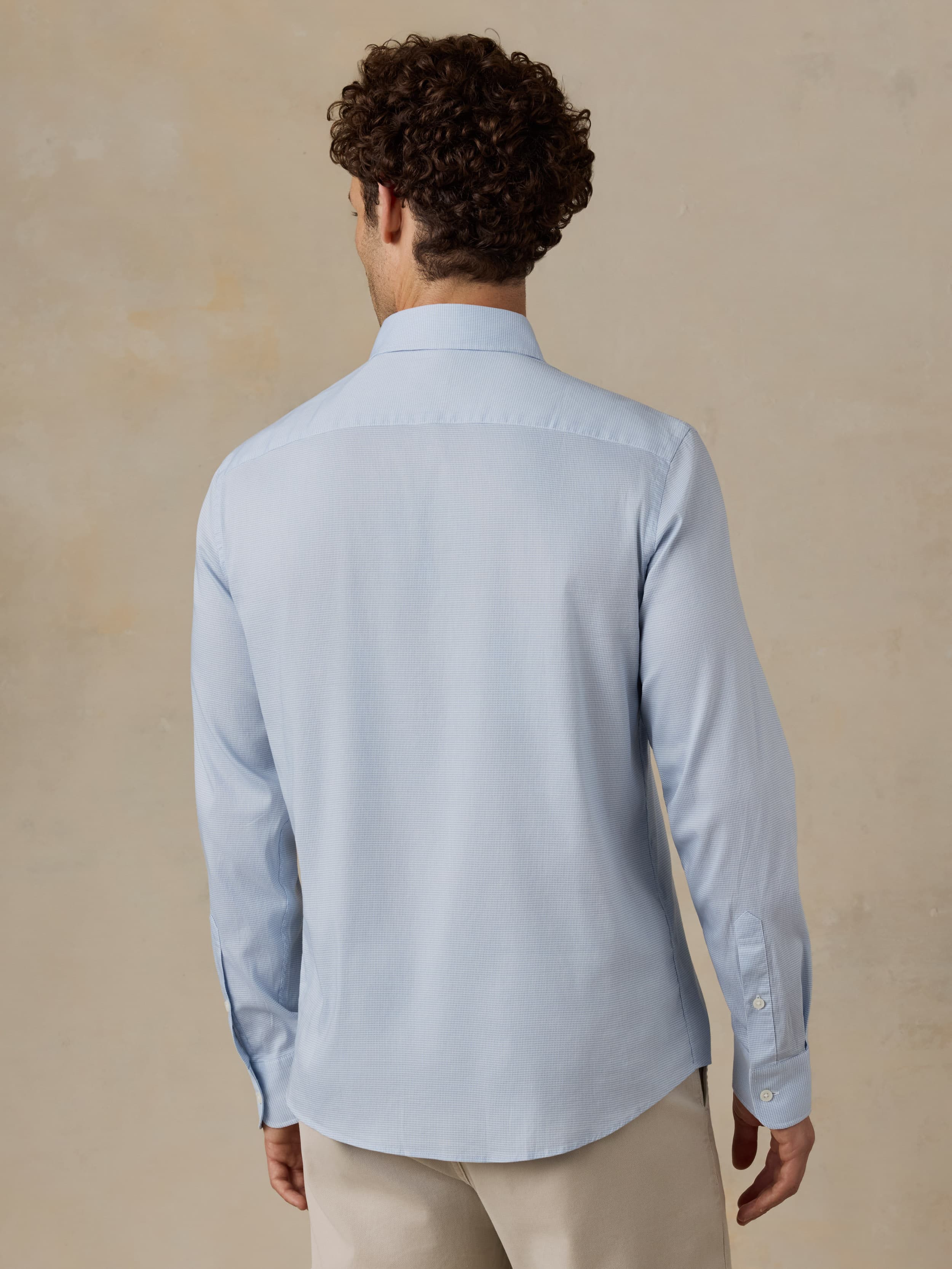 Man wearing a light blue shirt against a beige background