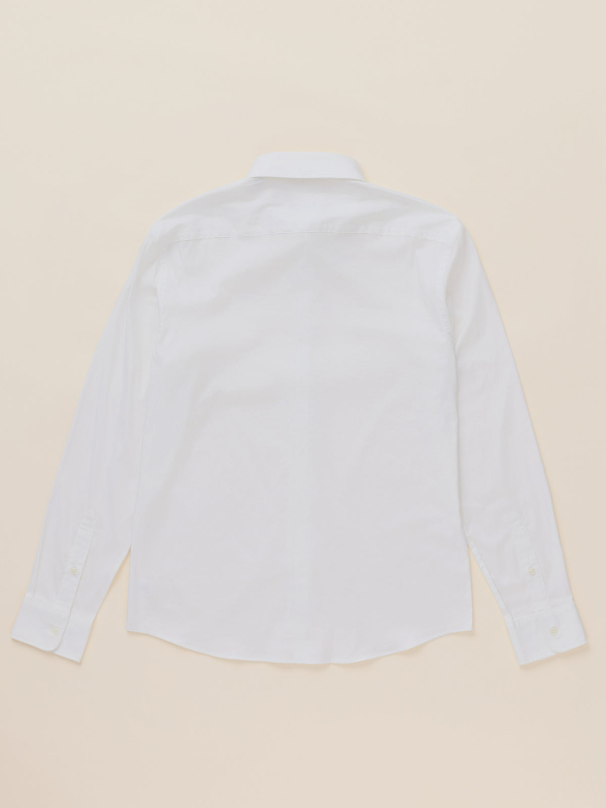 A white long-sleeve button-down shirt shown from the back, laid flat on a light beige background., image 7 of 7