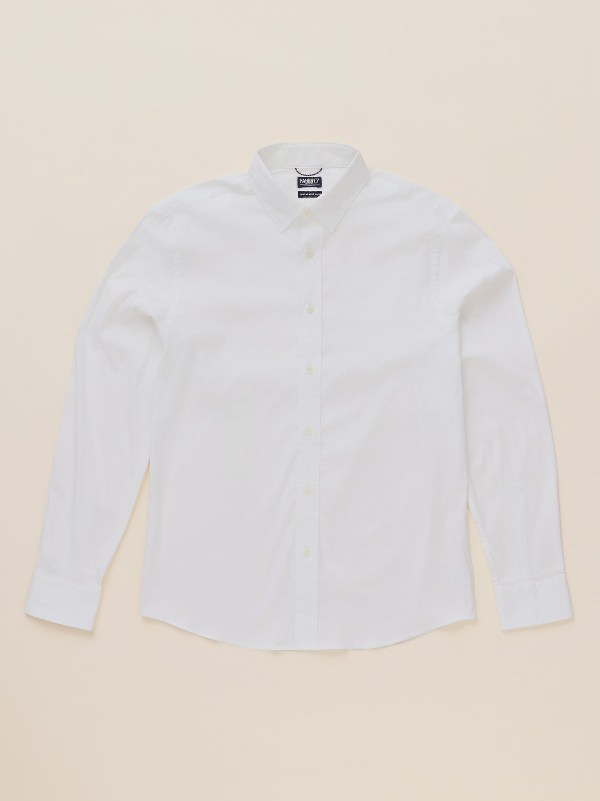 A white long-sleeve button-down shirt with a classic collar, laid flat against a solid, warm beige background., image 6 of 7