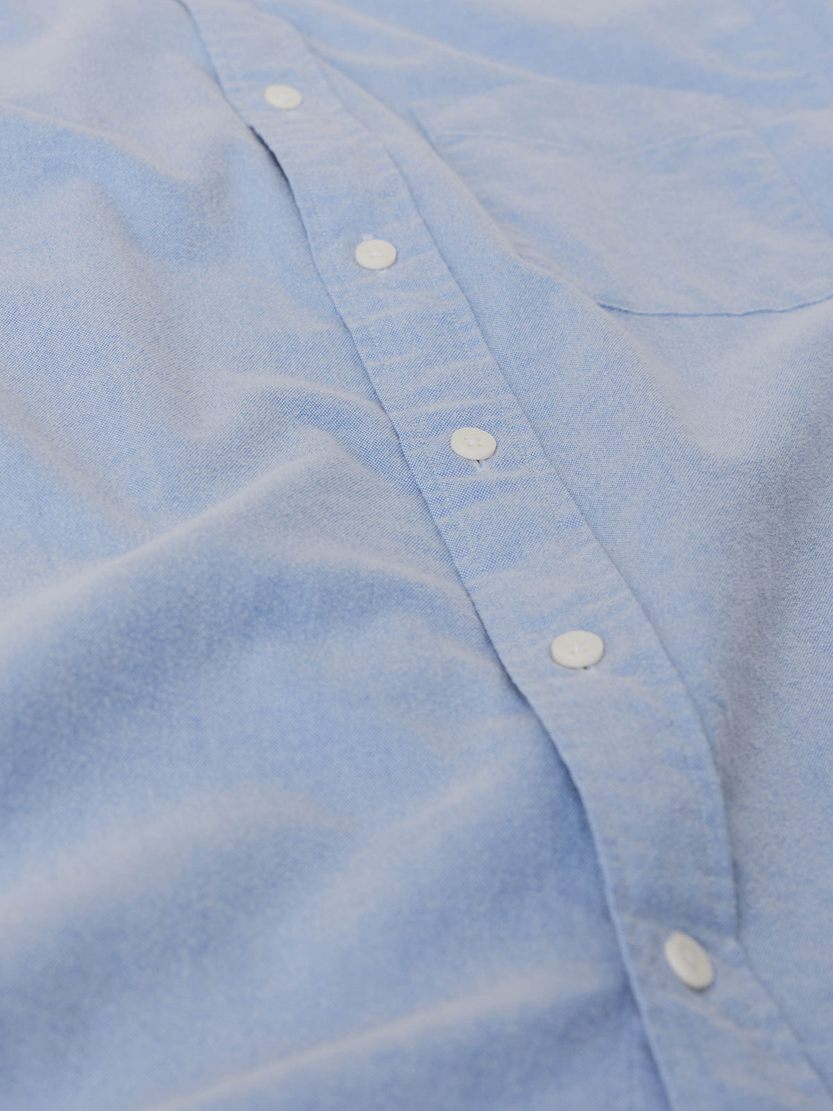 Close-up of a light blue button down shirt with white buttons, image 8 of 9