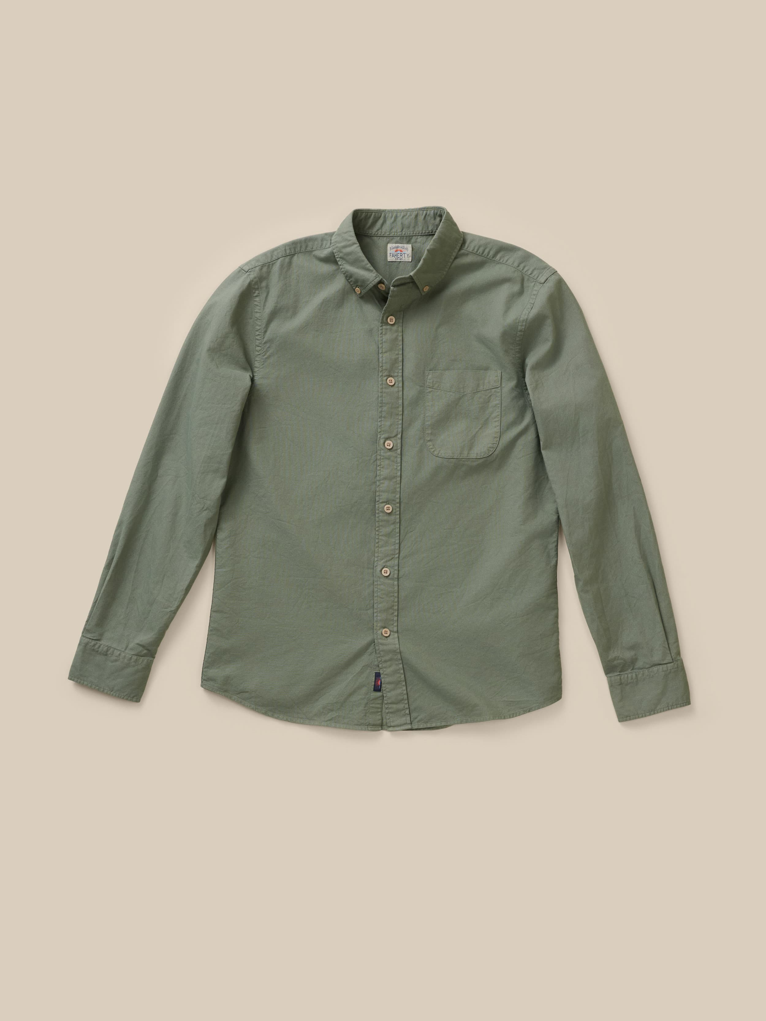 Olive green long sleeve button down shirt against a beige background