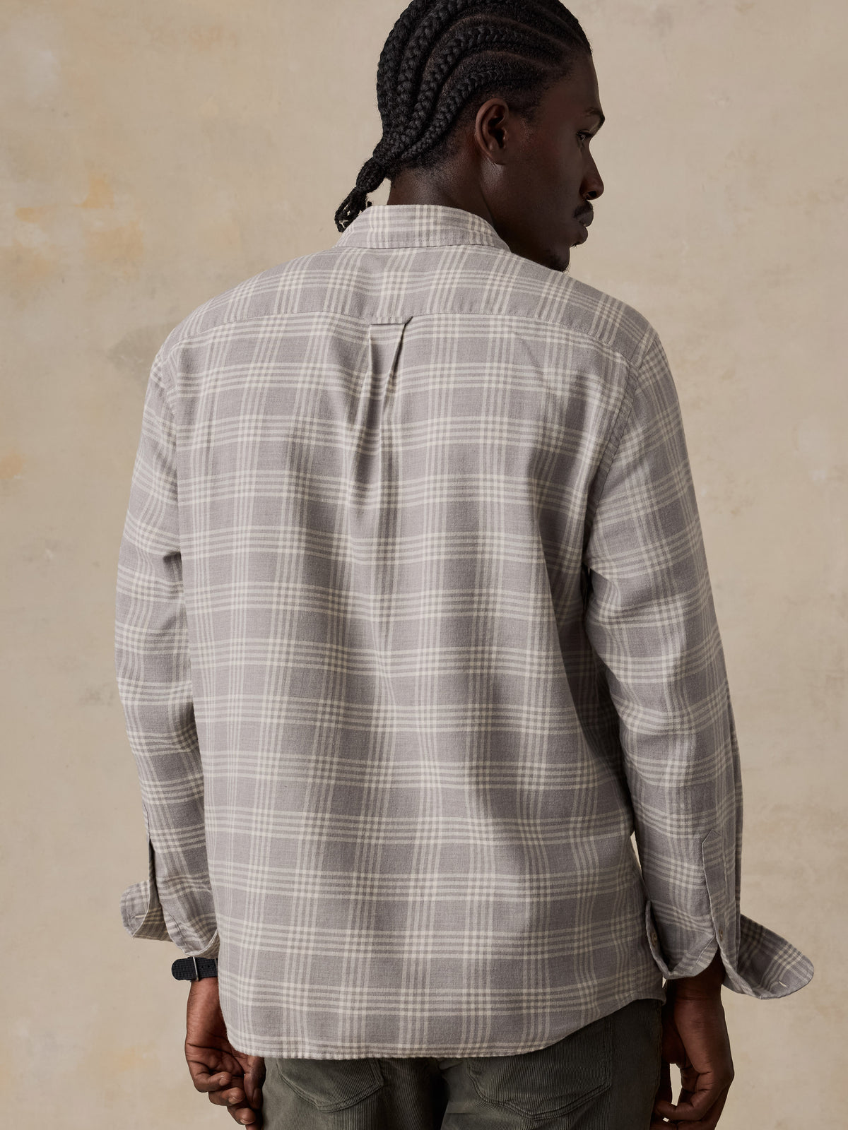 A man viewed from behind wearing a grey plaid button up shirt and green corduroy pants, image 4 of 5