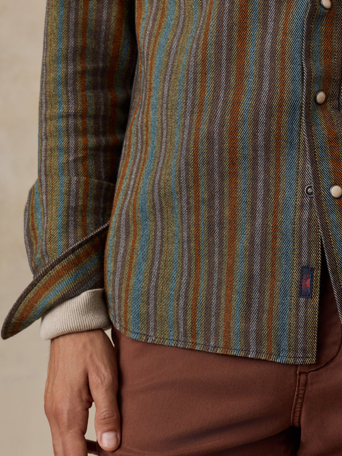 Close up of a man wearing a colorful western shirt with white snap buttons and a small Faherty brand tag near the hem, image 4 of 8