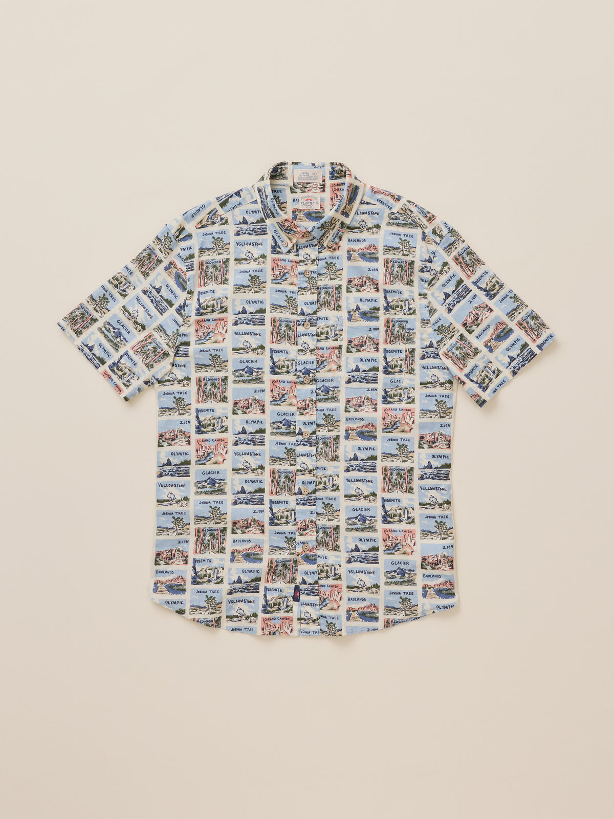 A short-sleeve button-up shirt with an all-over collage print of National Park scenes, laid flat on a light beige background., image 7 of 7