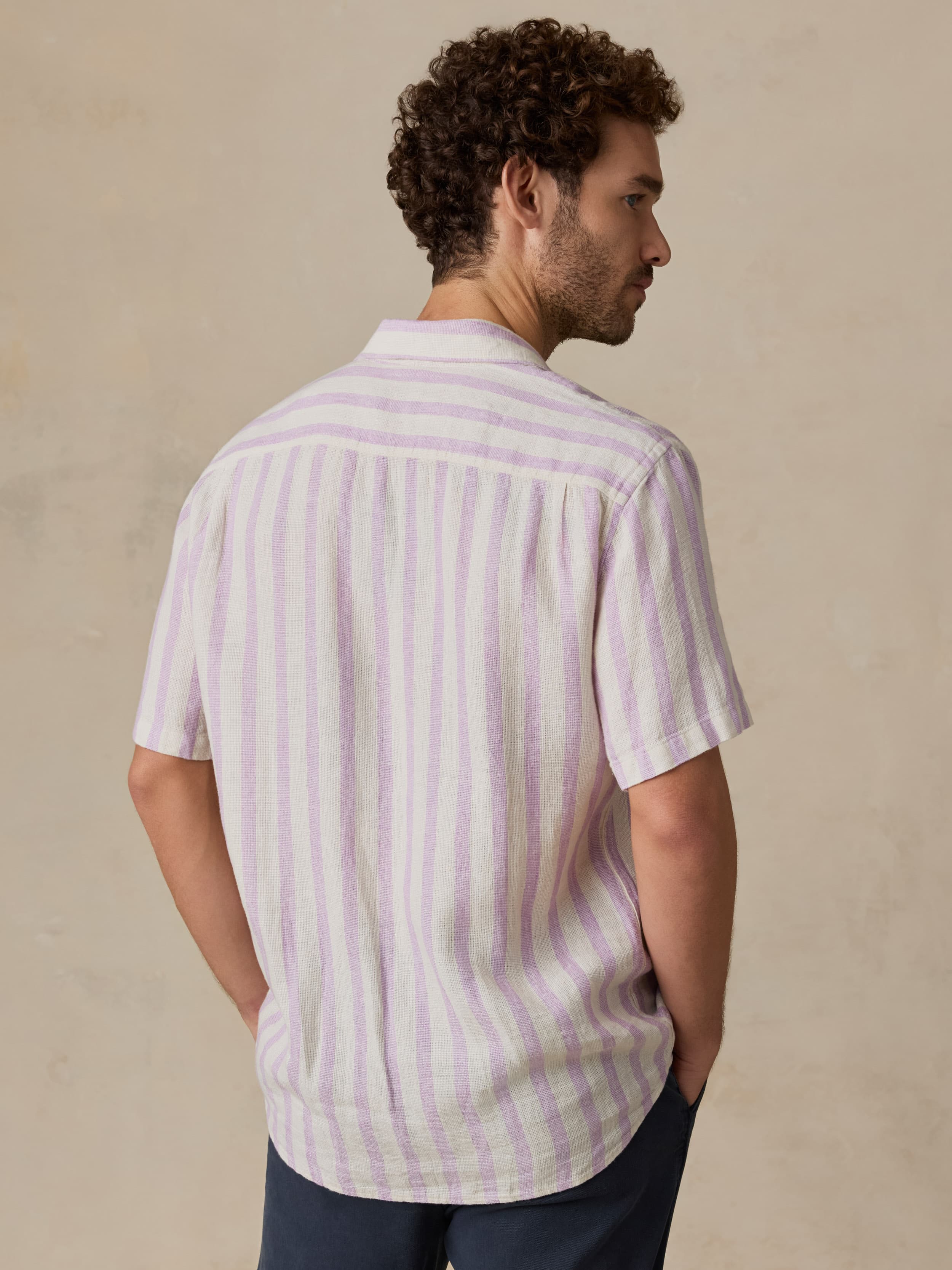 Man wearing a light purple striped shirt against a beige background