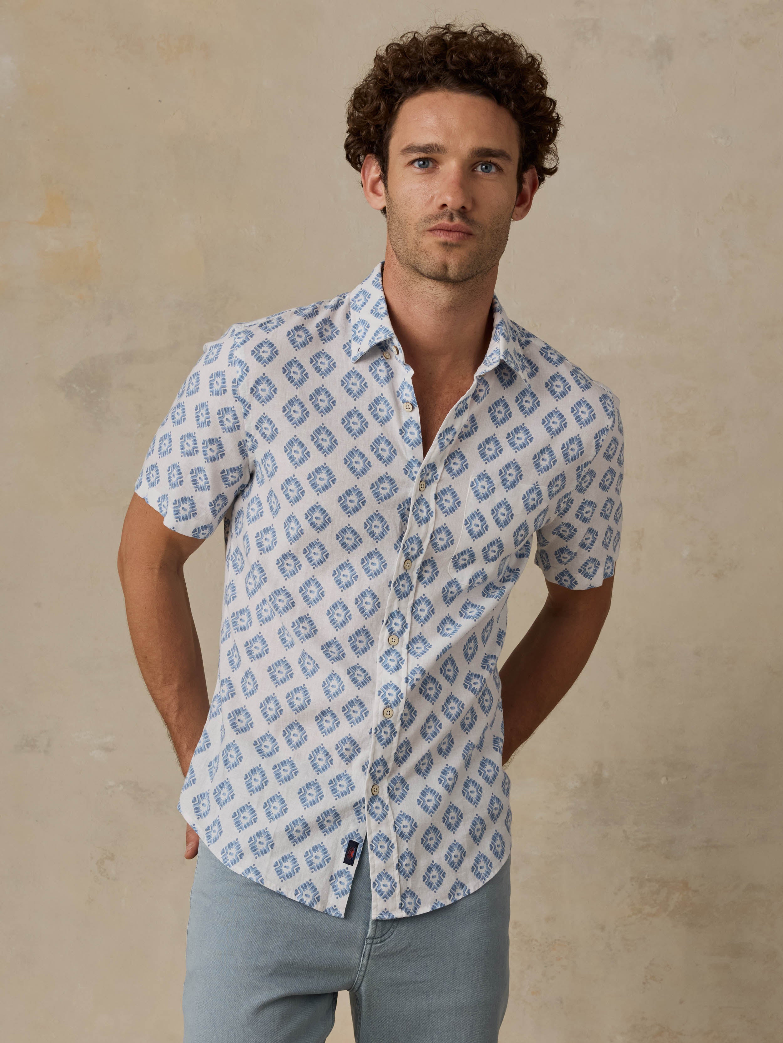 Man wearing a patterned blue and white shirt against a beige background