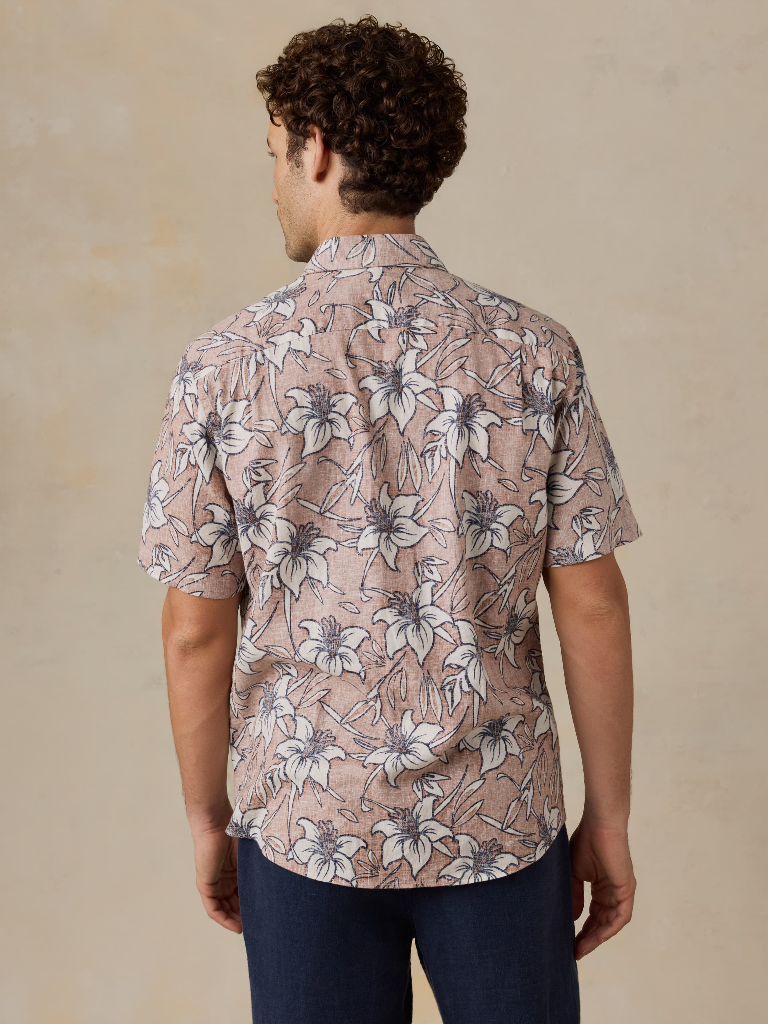 Man wearing a floral patterned shirt against a beige background