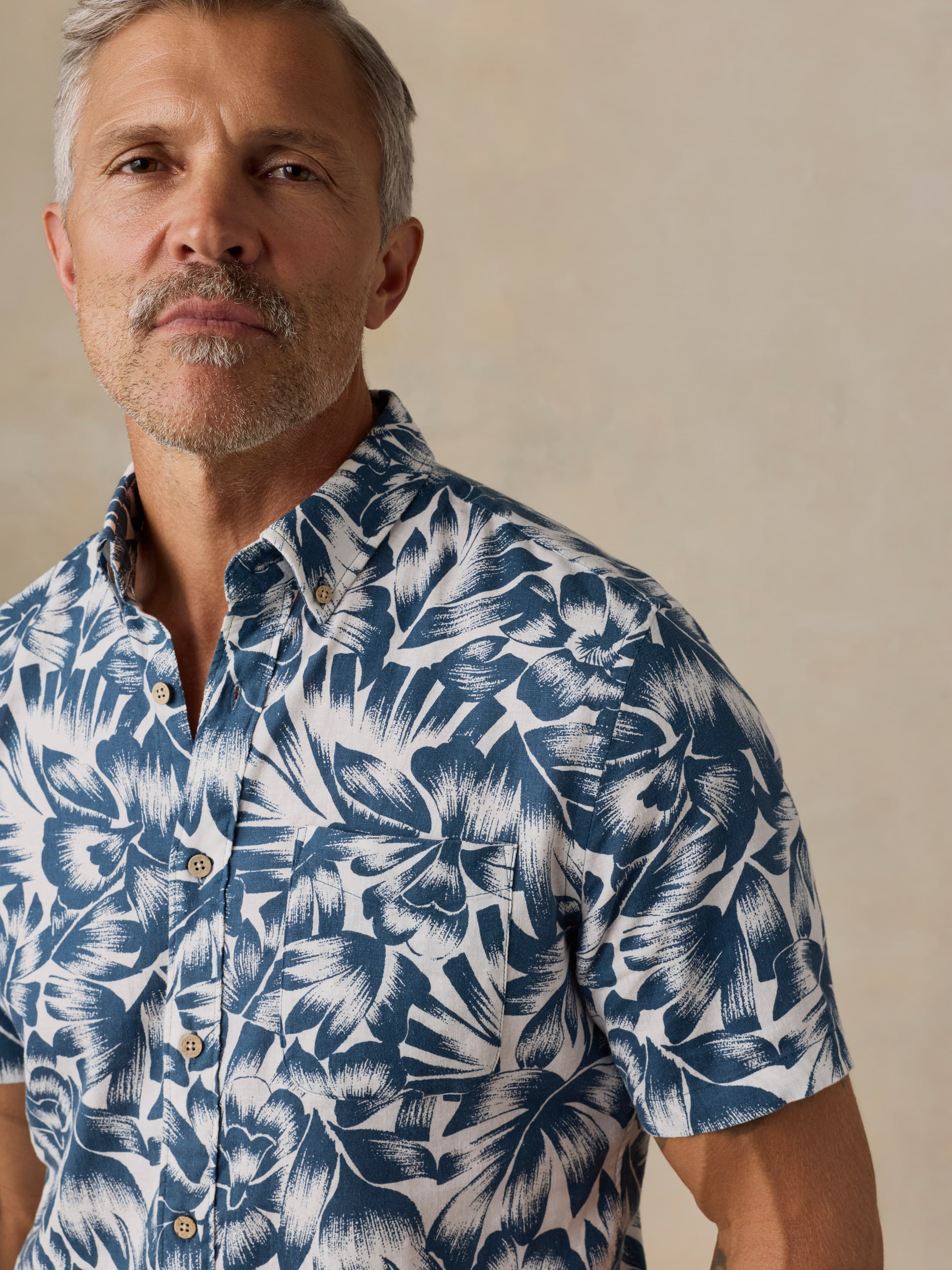 Man wearing a blue and white patterned shirt against a beige background