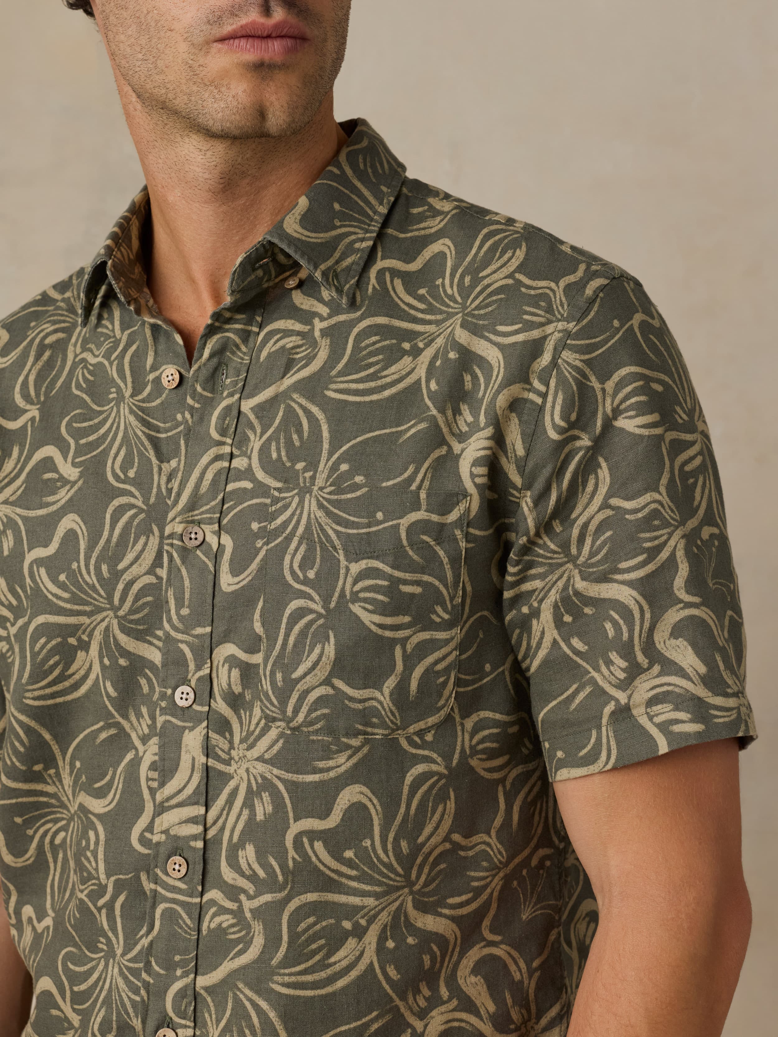 Man wearing a green floral printed shirt against a beige background