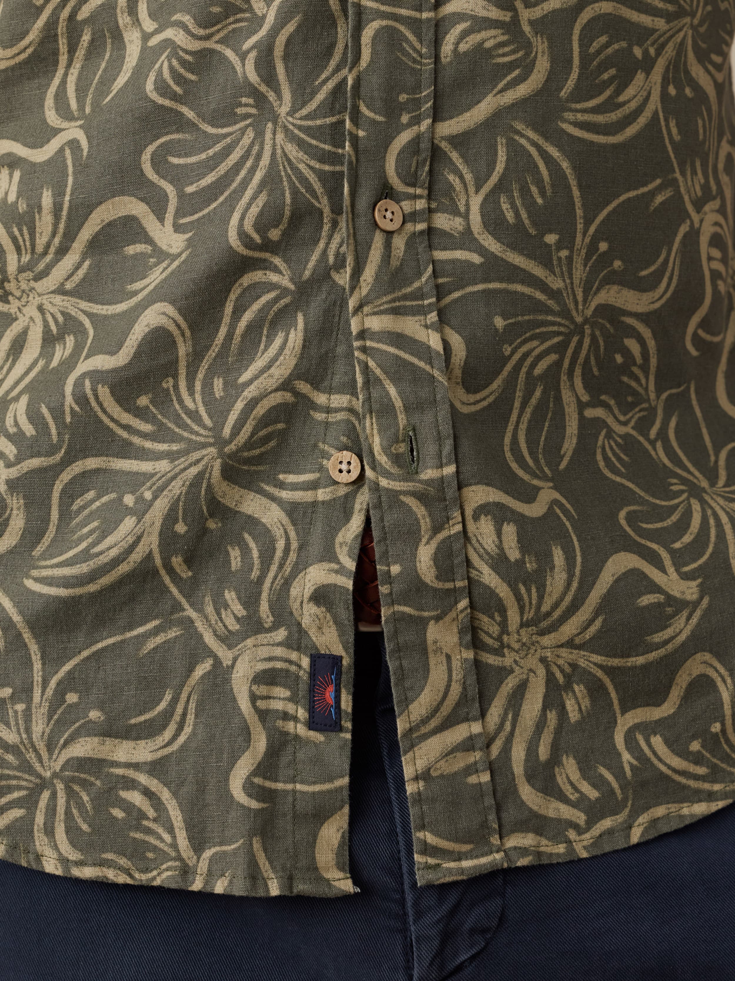 Green shirt with beige floral pattern and Faherty brand logo near the hem