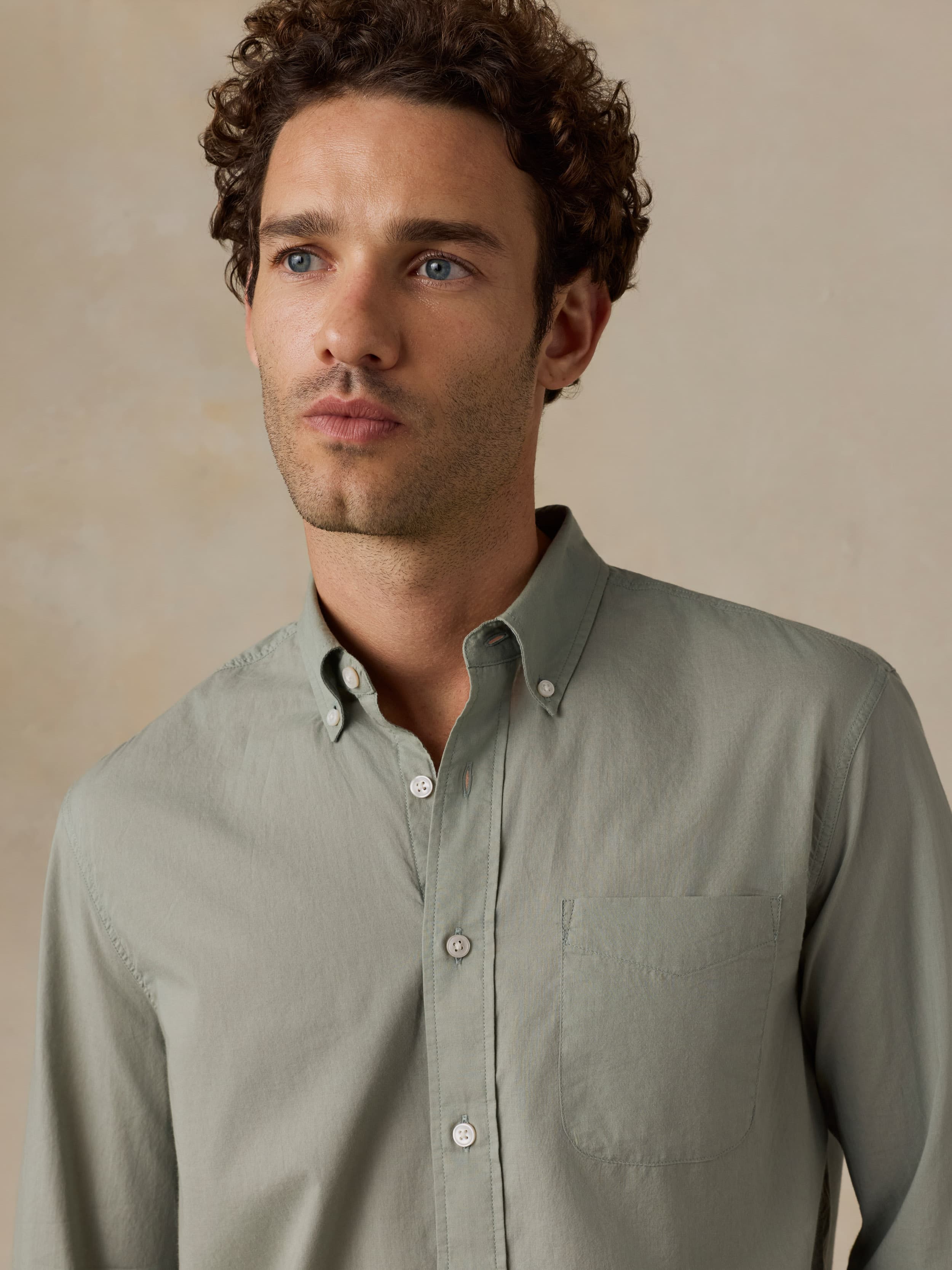 Man wearing a light green shirt against a beige background