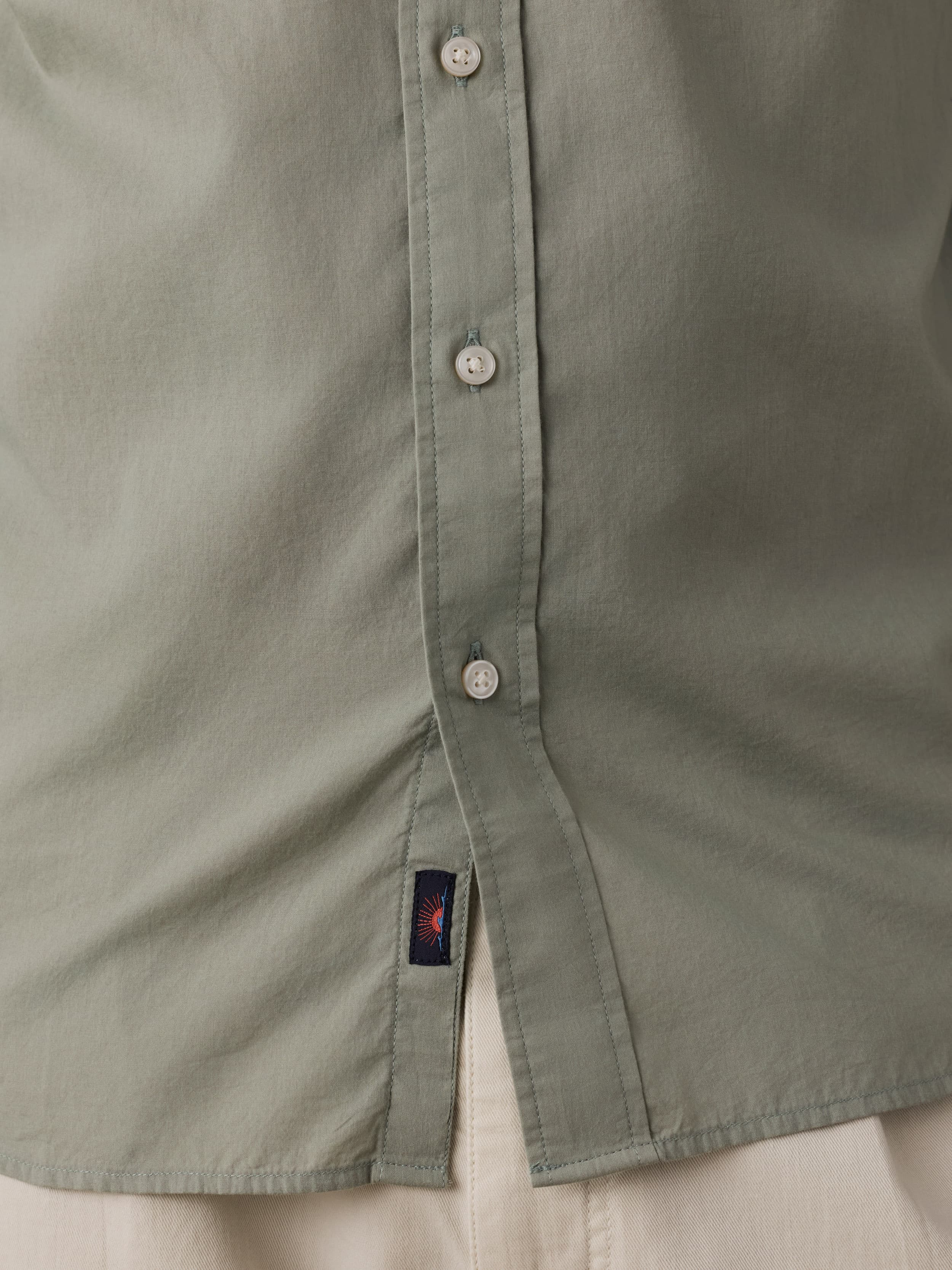 Close-up of a green shirt with a Faherty brand label near the hem