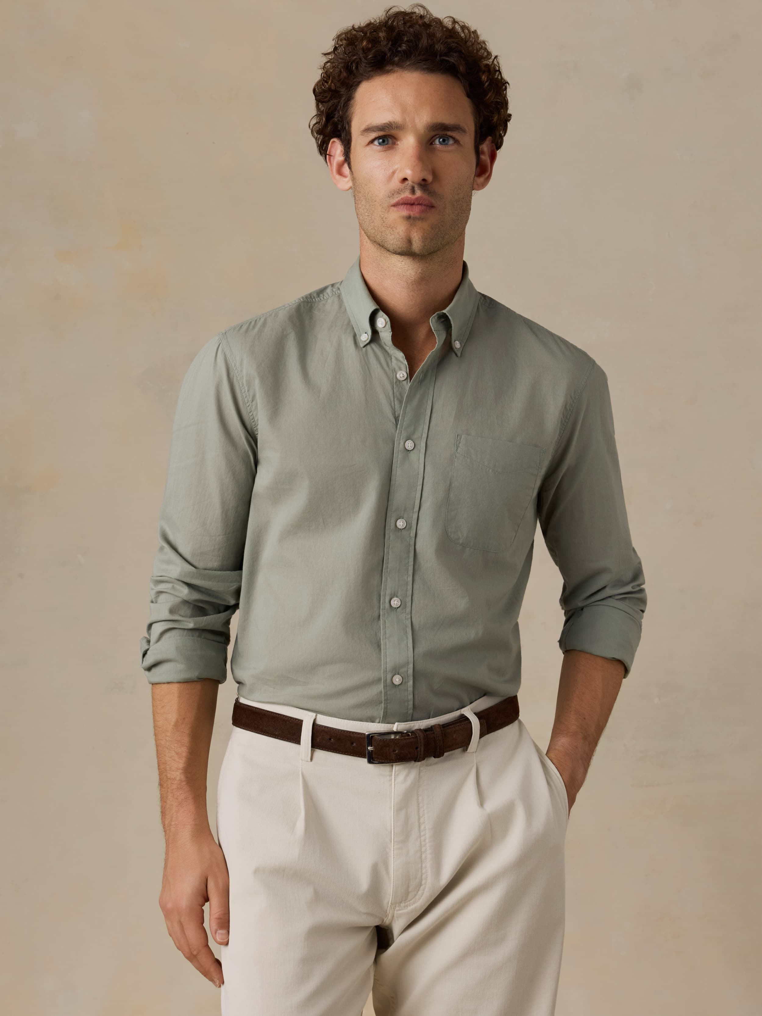 Man wearing a light green shirt and beige pants against a beige background