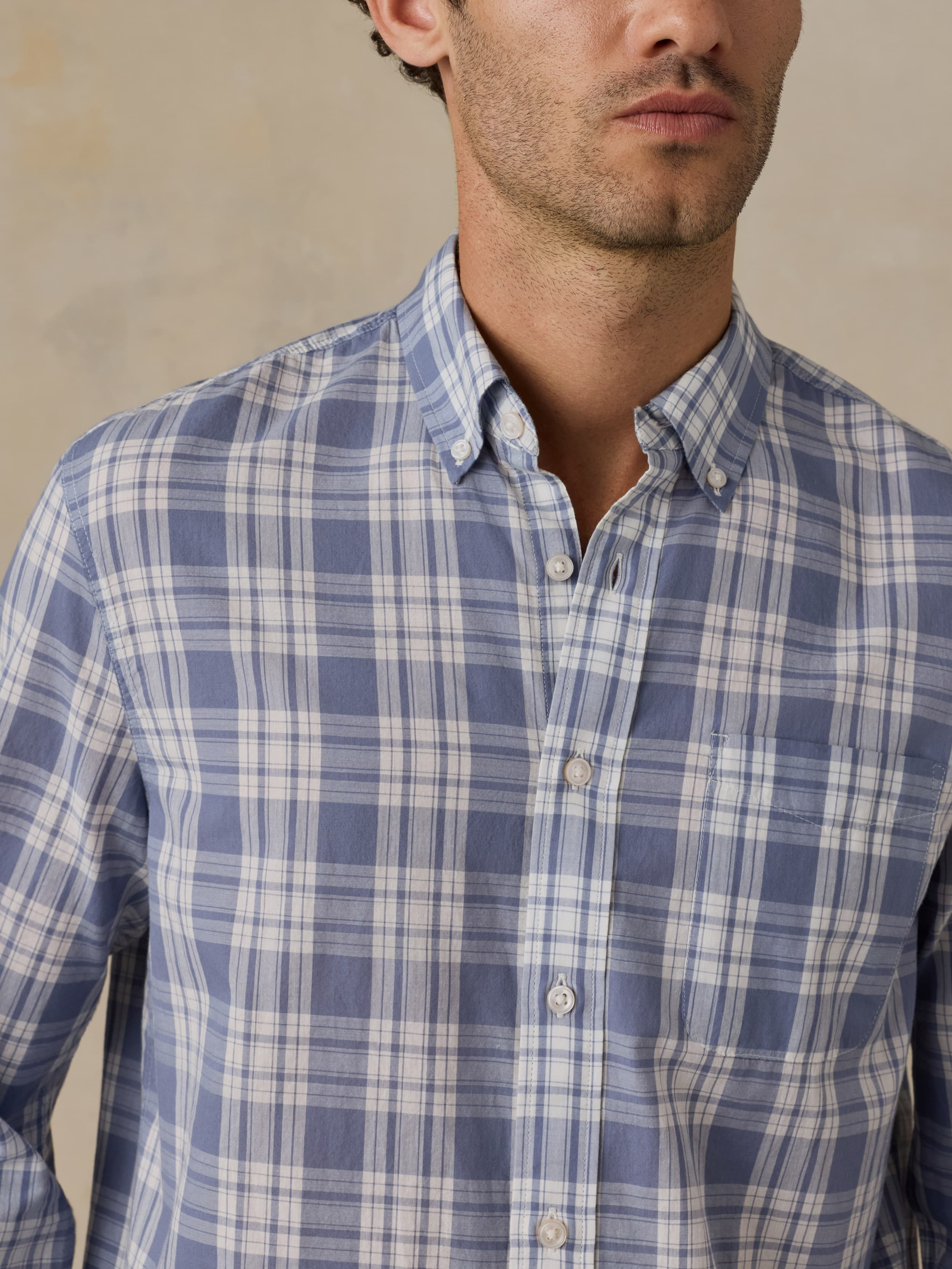 Man wearing a blue and white checkered shirt against a neutral background