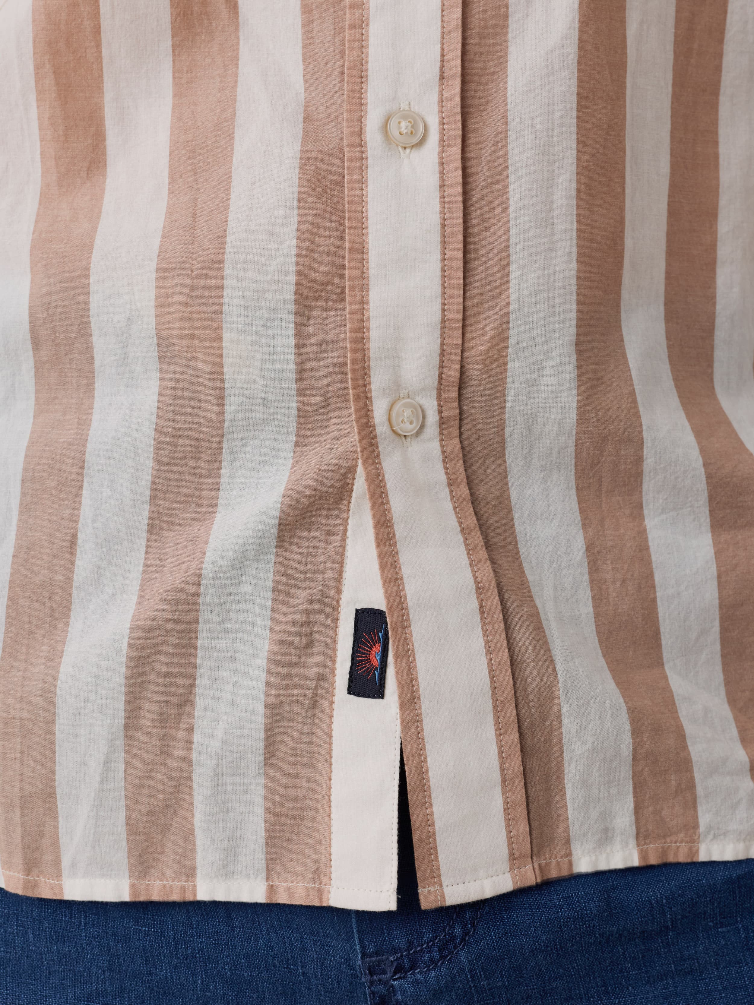 Close-up of a striped shirt with a Faherty brand label near the hem