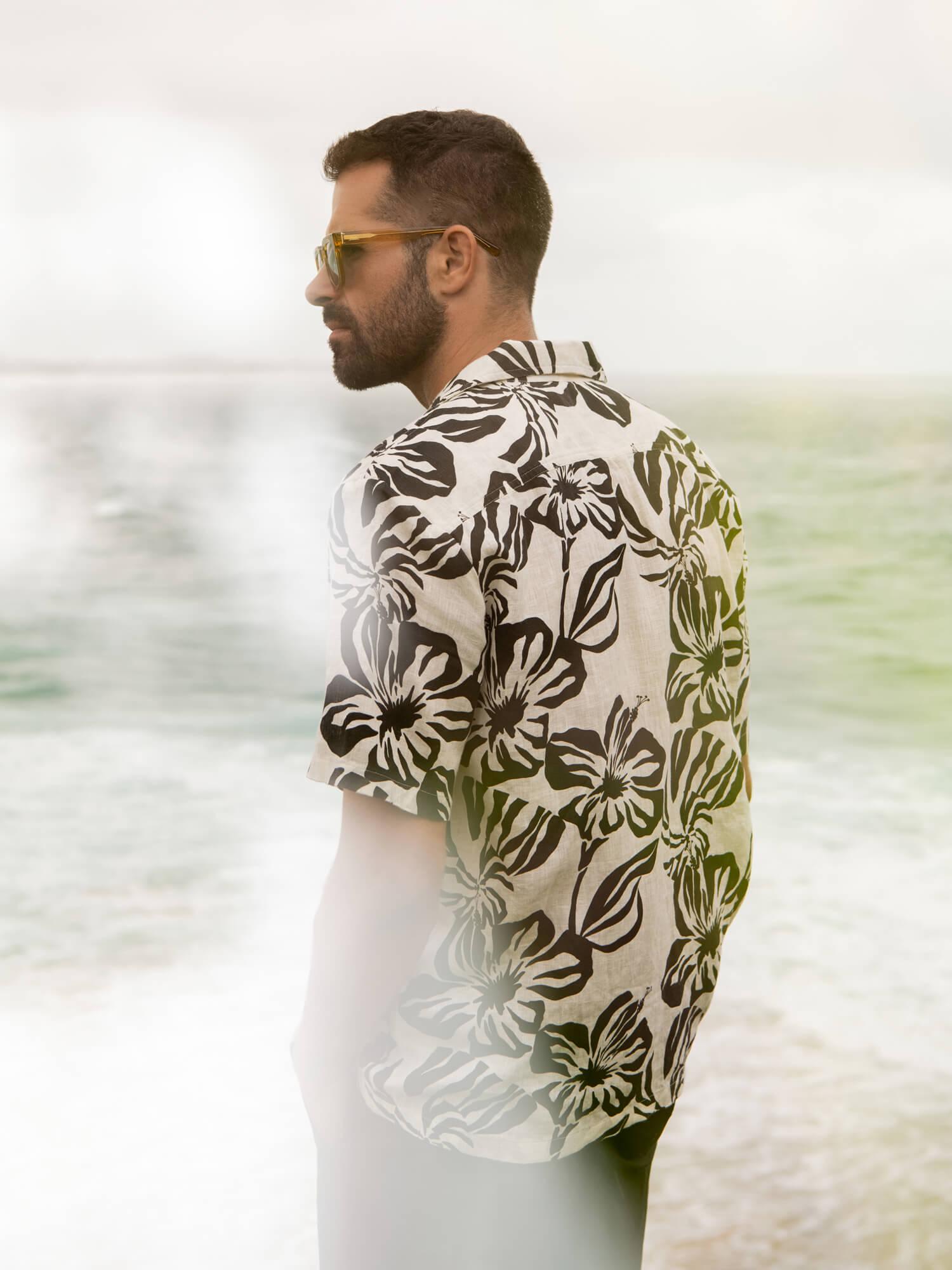 Man wearing a black and white floral printed shirt at the beach