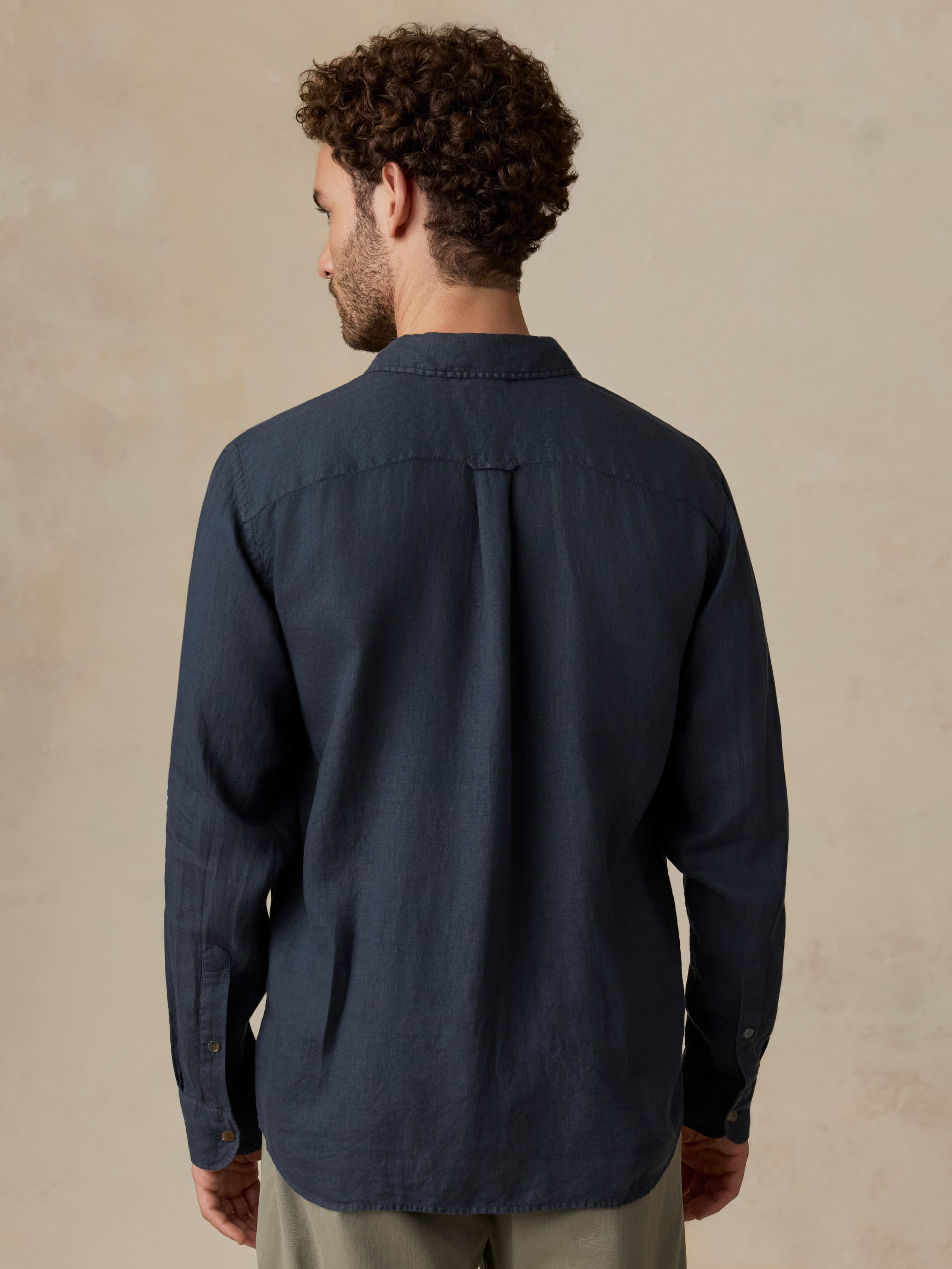 Man wearing a navy blue shirt against a beige background