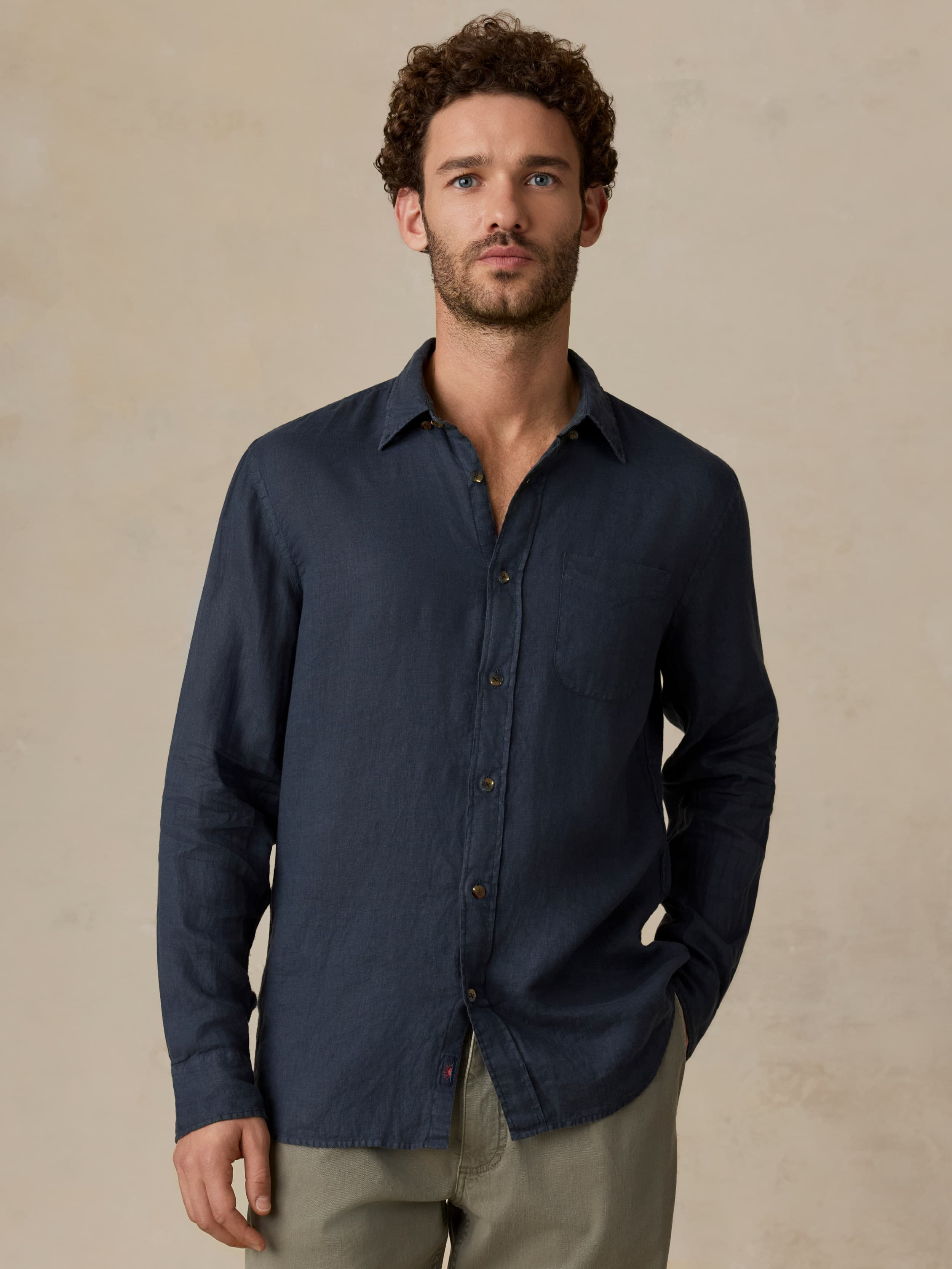 Man wearing a navy button-up shirt against a beige background