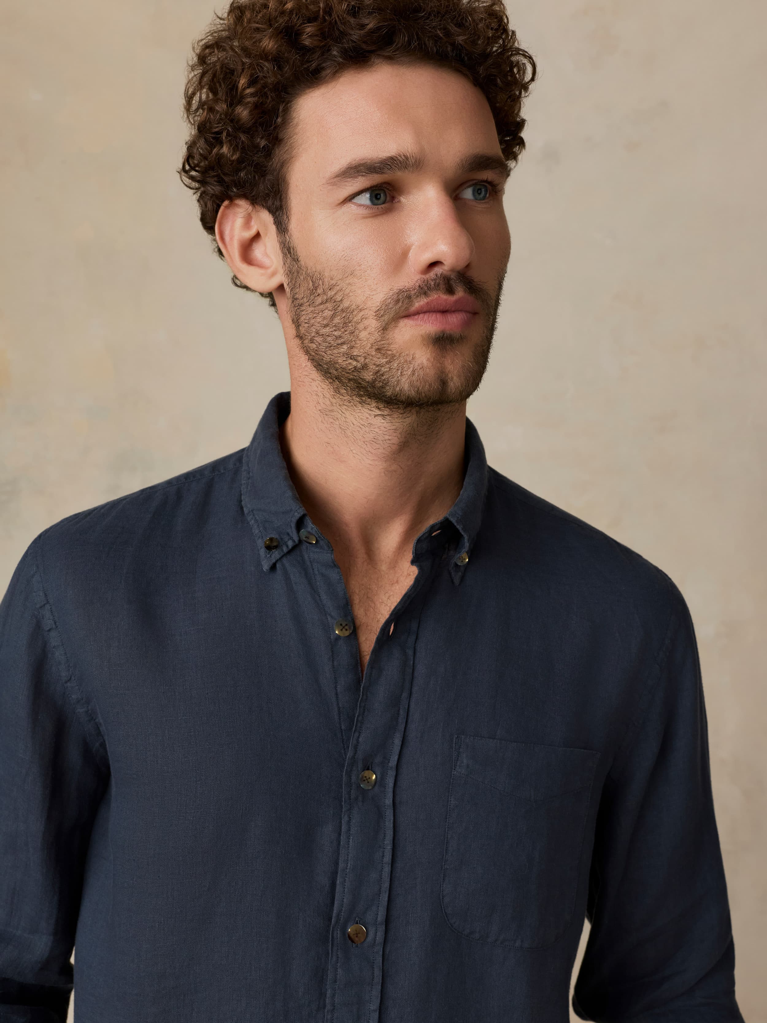 Man wearing a dark blue shirt against a beige background