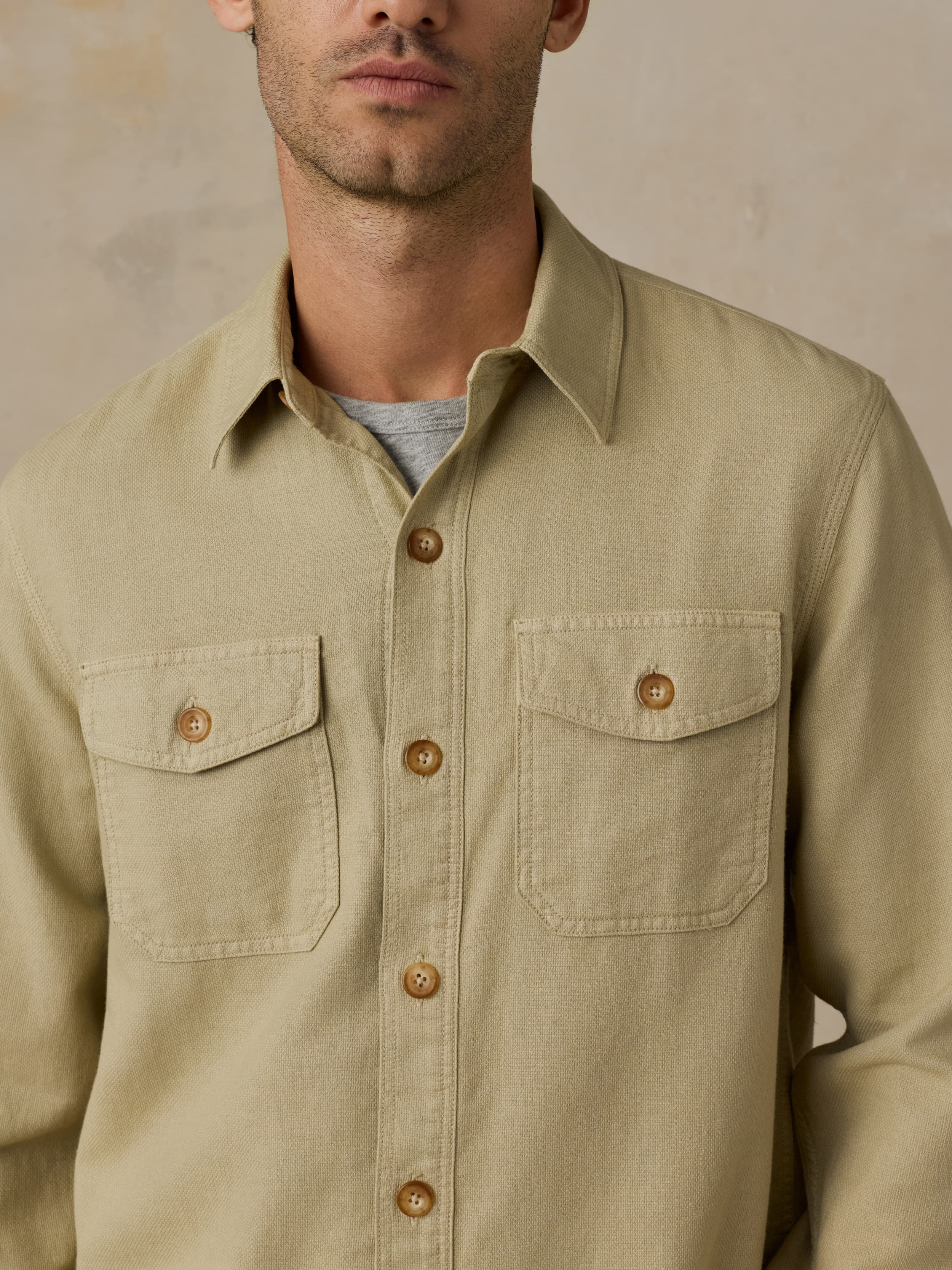 Man wearing a beige button down shirt against a beige background