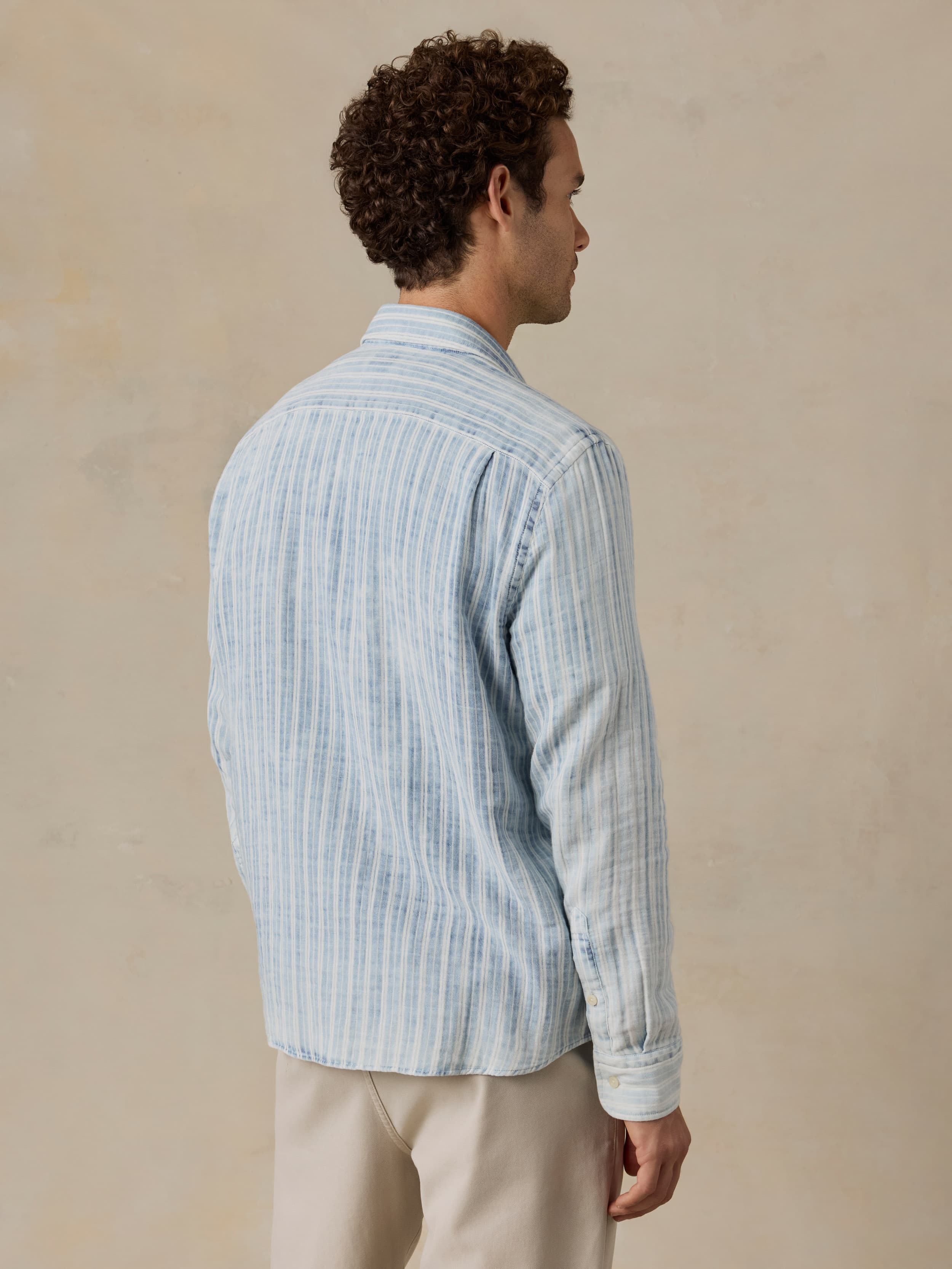 Man wearing a light blue striped shirt against a beige background