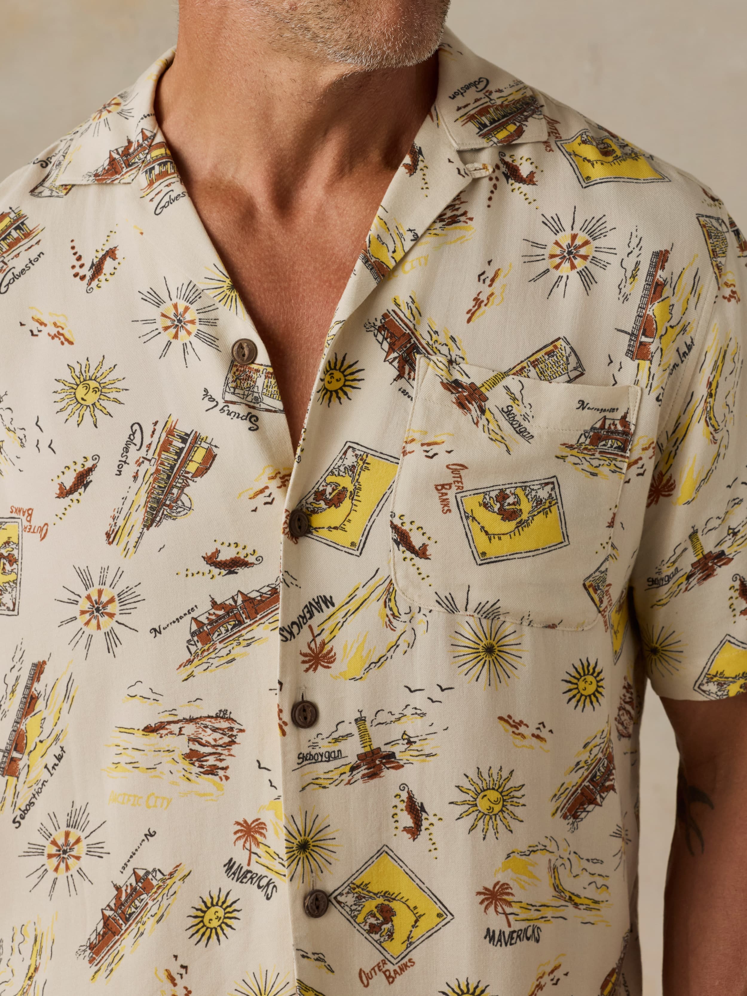 Man wearing a patterned shirt with vintage-style graphics on a neutral background
