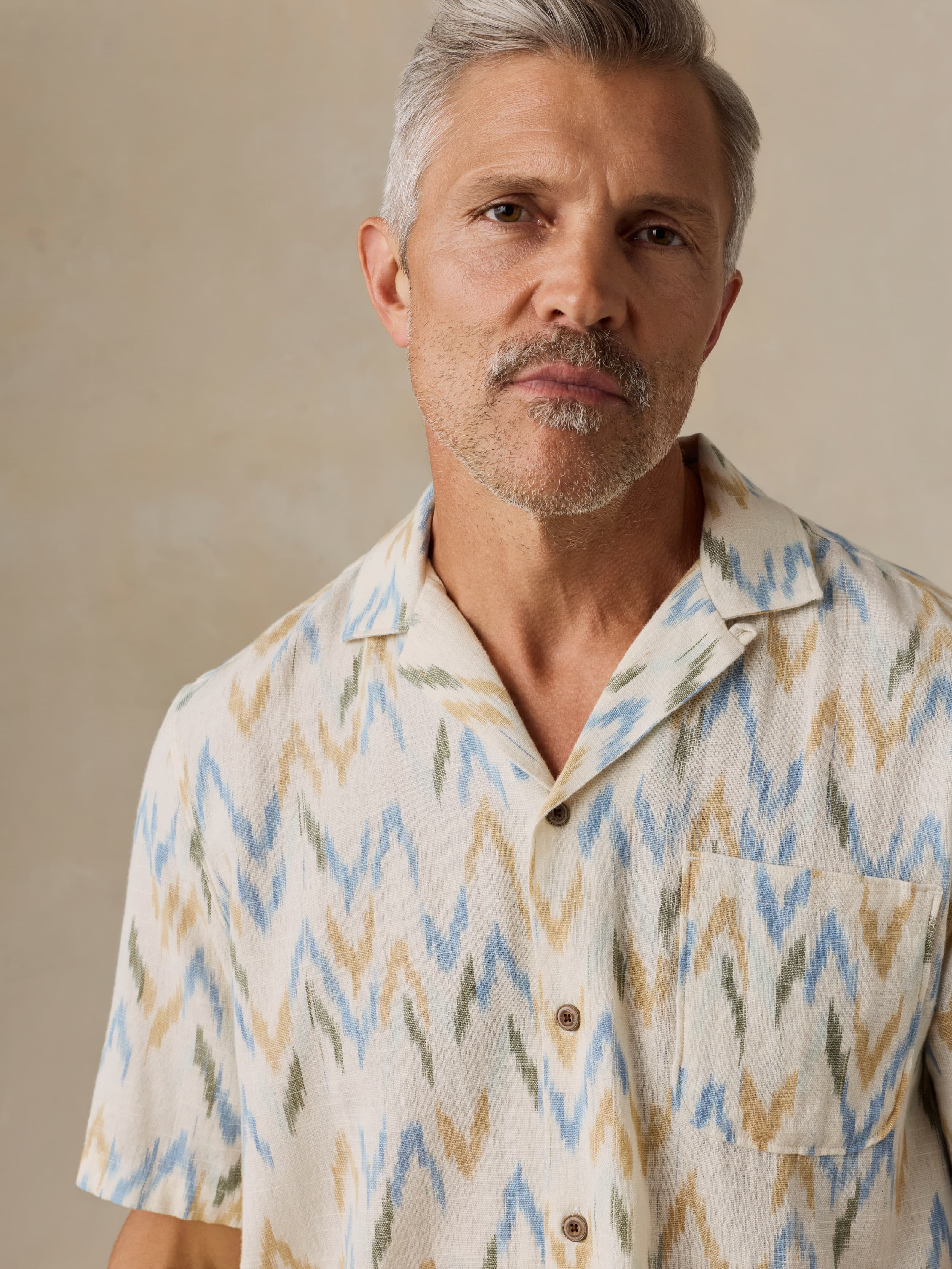 Man wearing a patterned shirt against a beige background