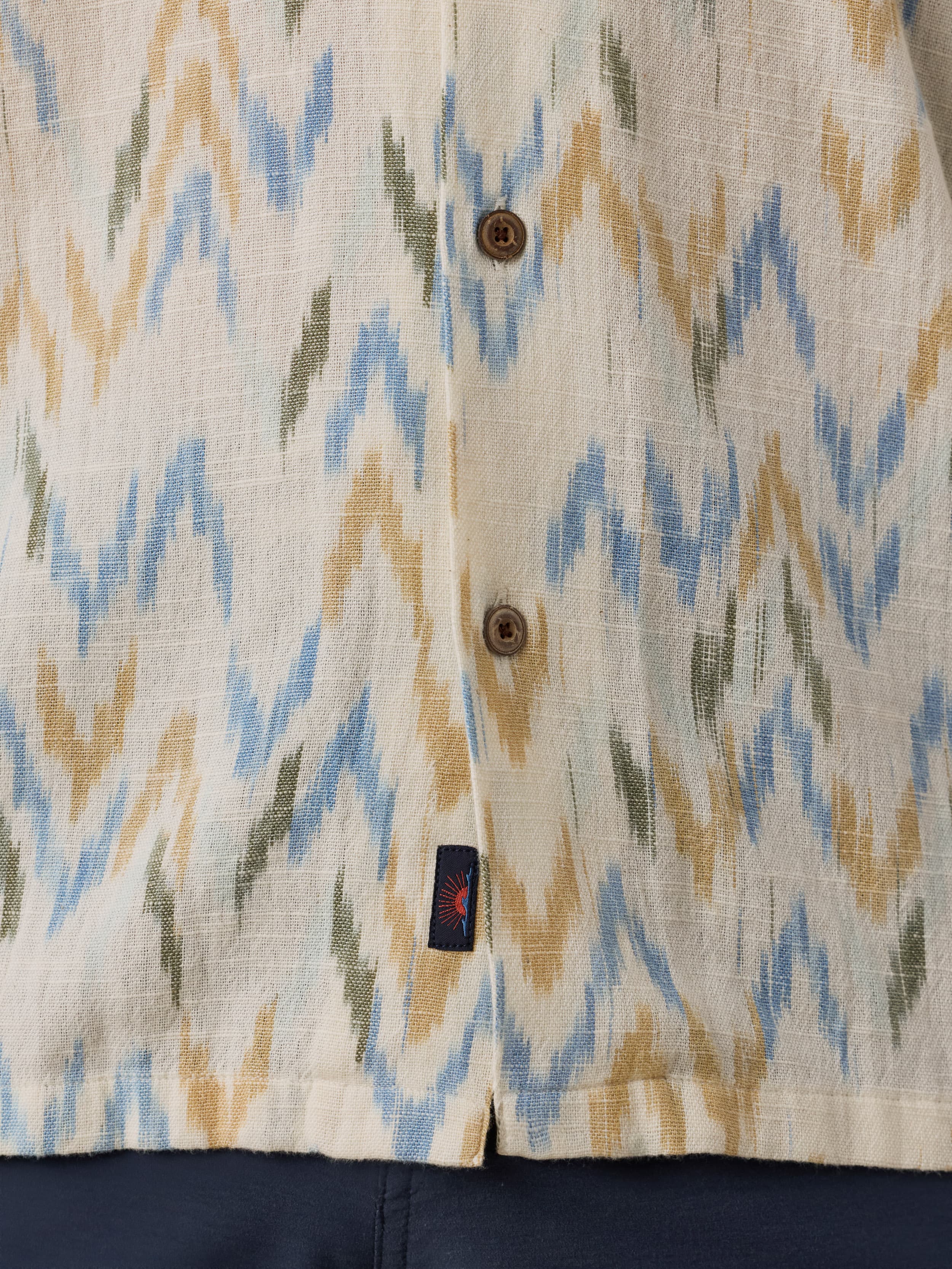 Close-up of a patterned shirt with a Faherty brand logo on a beige background