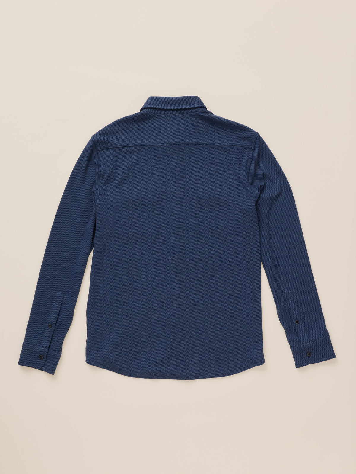 A dark blue long-sleeve button-up shirt shown from the back, laid flat against a light beige background., image 8 of 8