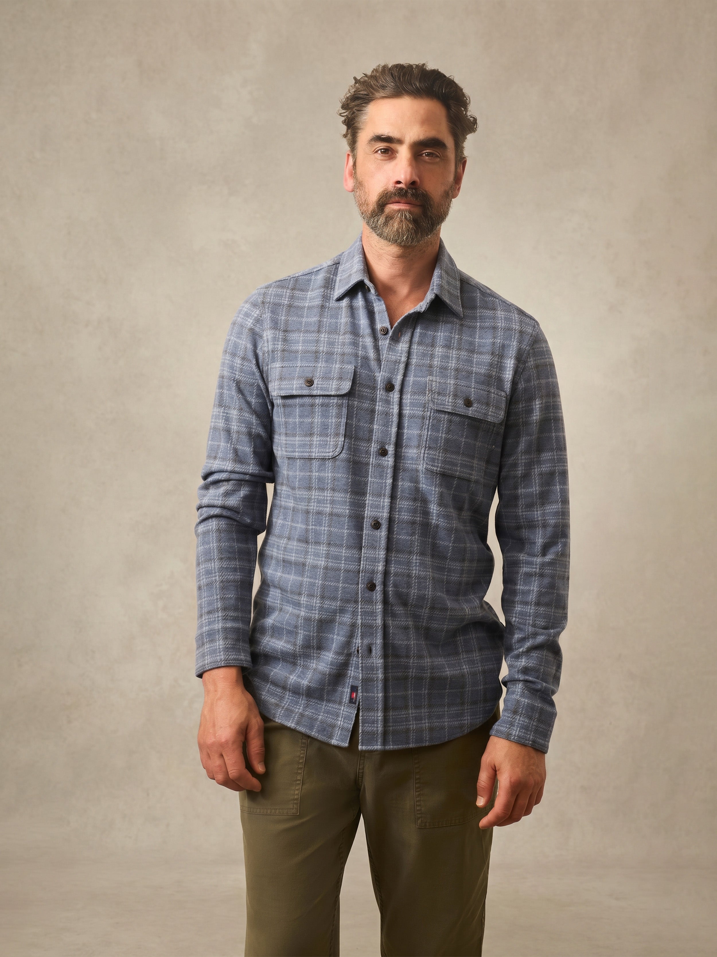 Man wearing a blue plaid shirt against a beige background
