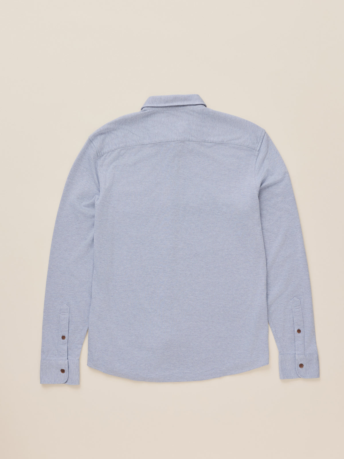 A light blue long-sleeve button-up shirt shown from the back, laid flat against a solid beige background., image 7 of 7