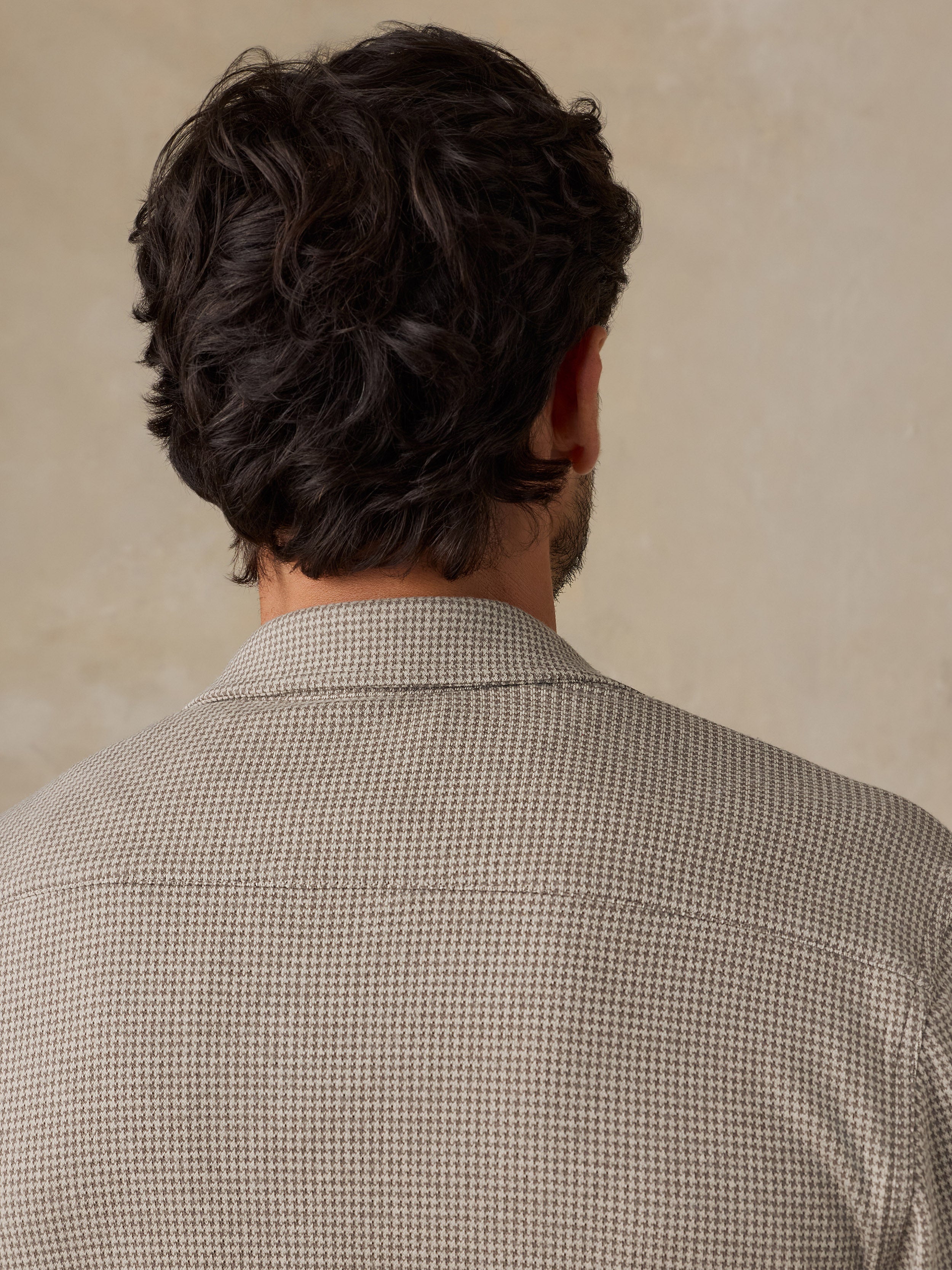 Man wearing a beige overshirt against a beige studio background