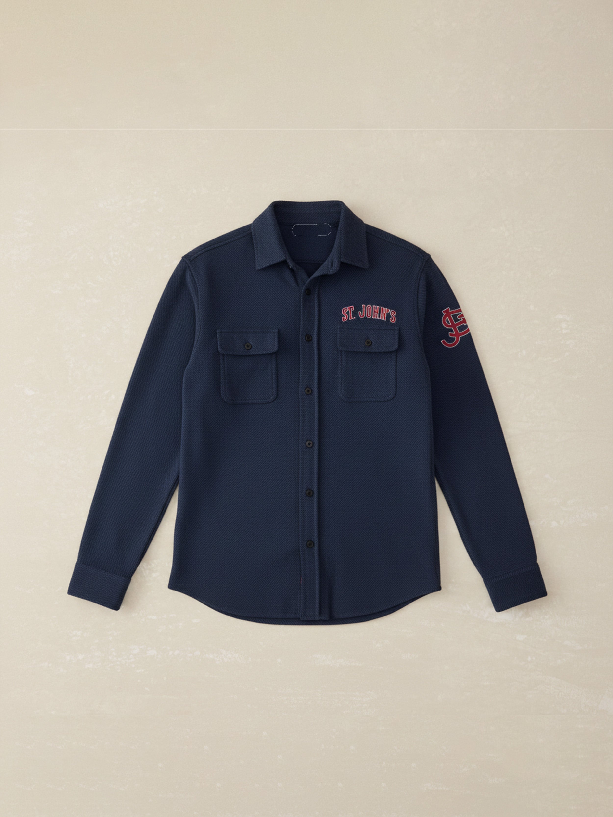 Navy shirt with St. John's graphics at the left chest and left arm against a beige background