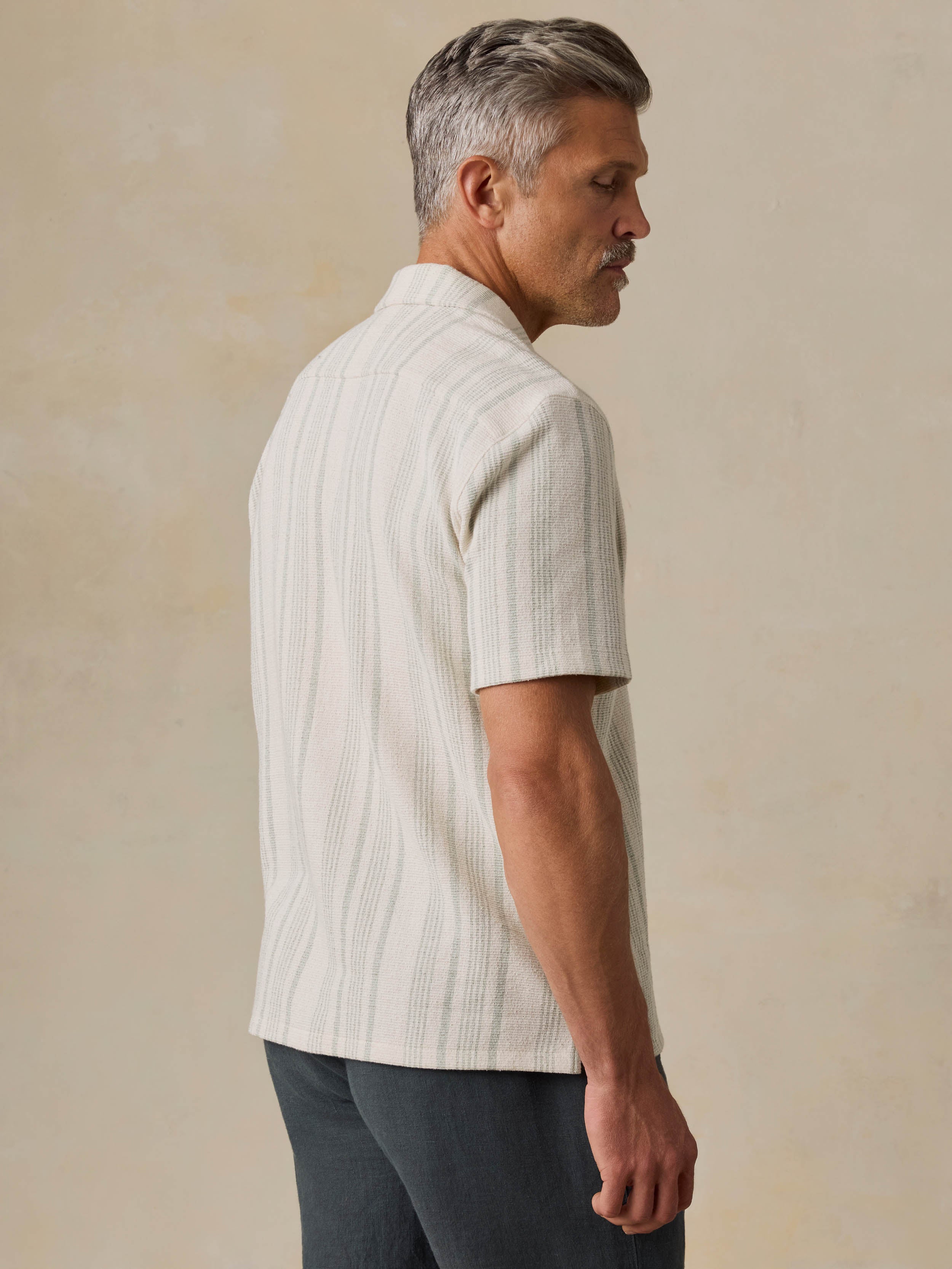 Man wearing a beige striped shirt against a beige background