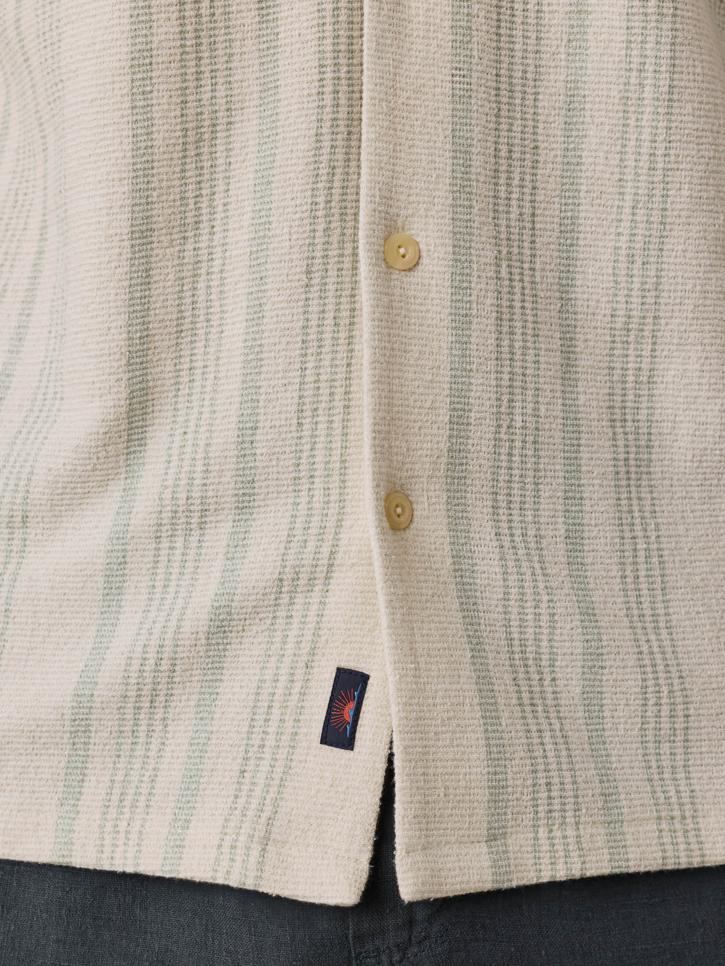 Close-up of a textured shirt with button details and a visible Faherty brand logo.